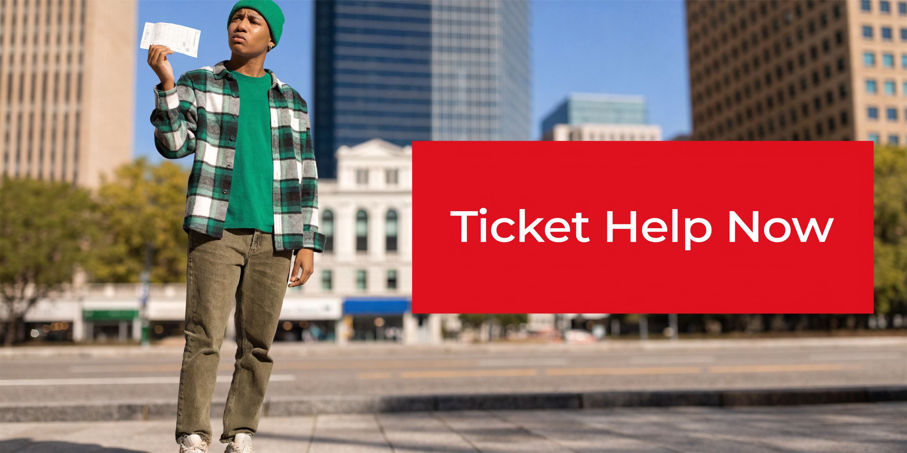 A young man holding a parking ticket while standing on a city street near tall buildings.