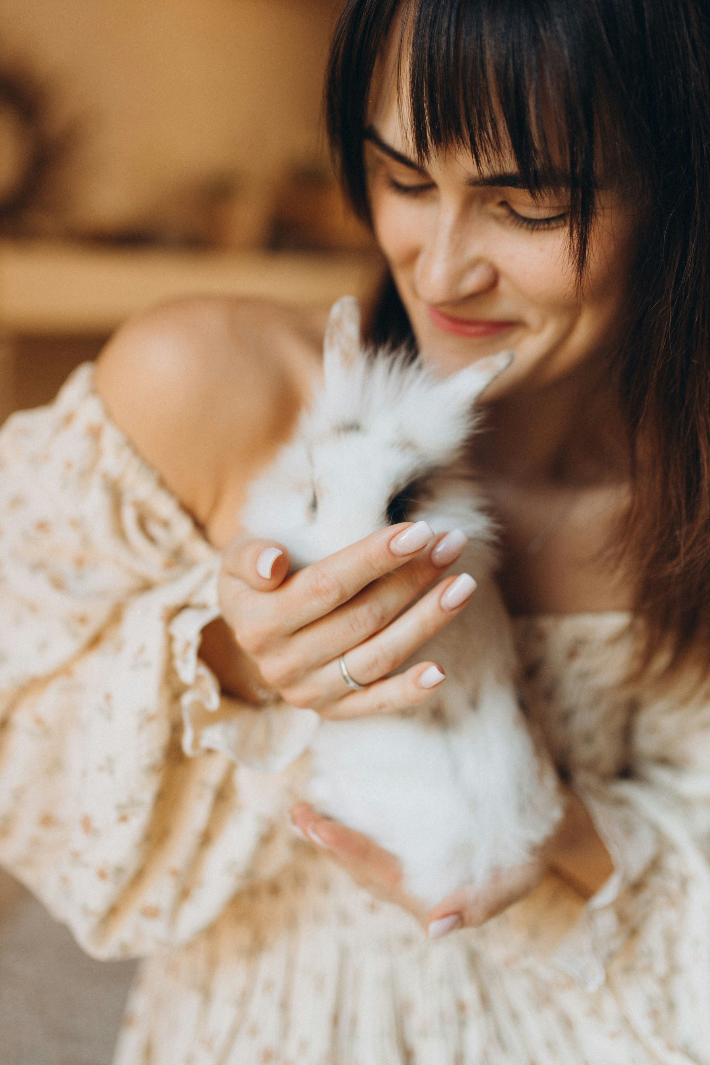 A woman gently holding a small white rabbit