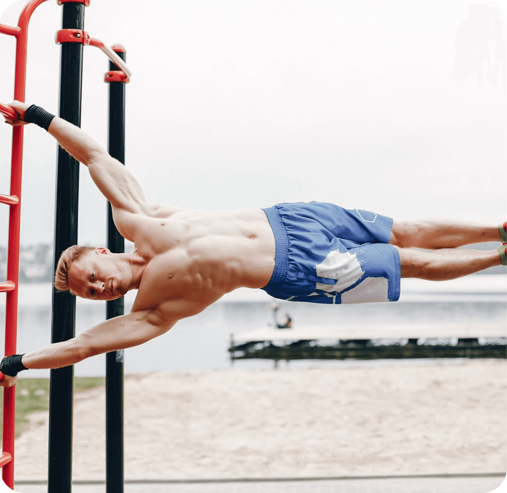 Man performing a human flag on outdoor bars by the beach.