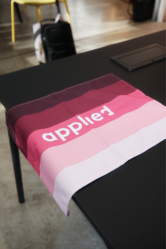 Tisch mit einer applied by zeb-Fahne und Laptop.