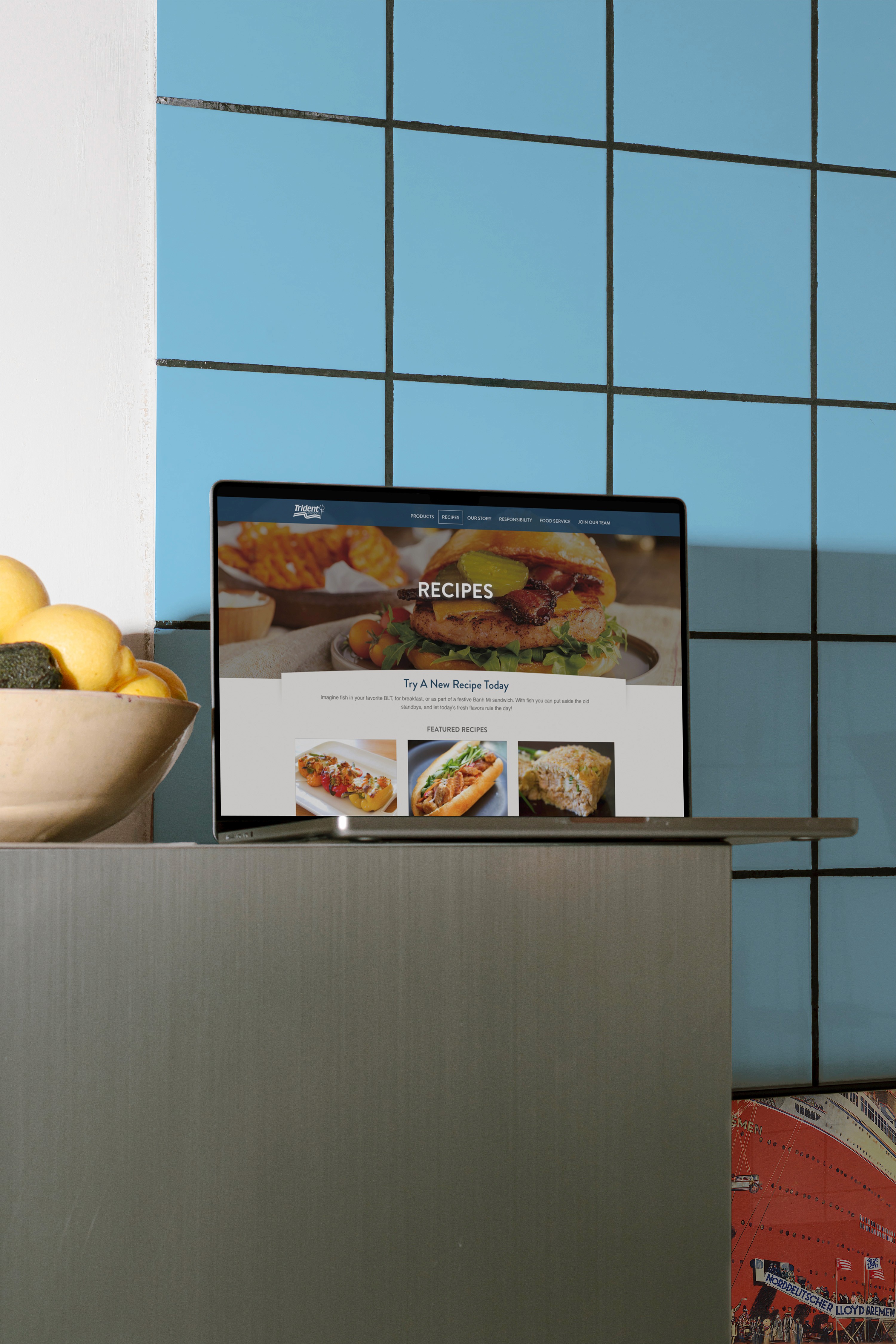 Laptop on counter against a tile wall showing the Trident Website