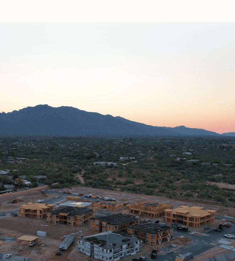 Aerial view of a construction site surrounded by mountains, showcasing ongoing development against a natural backdrop.