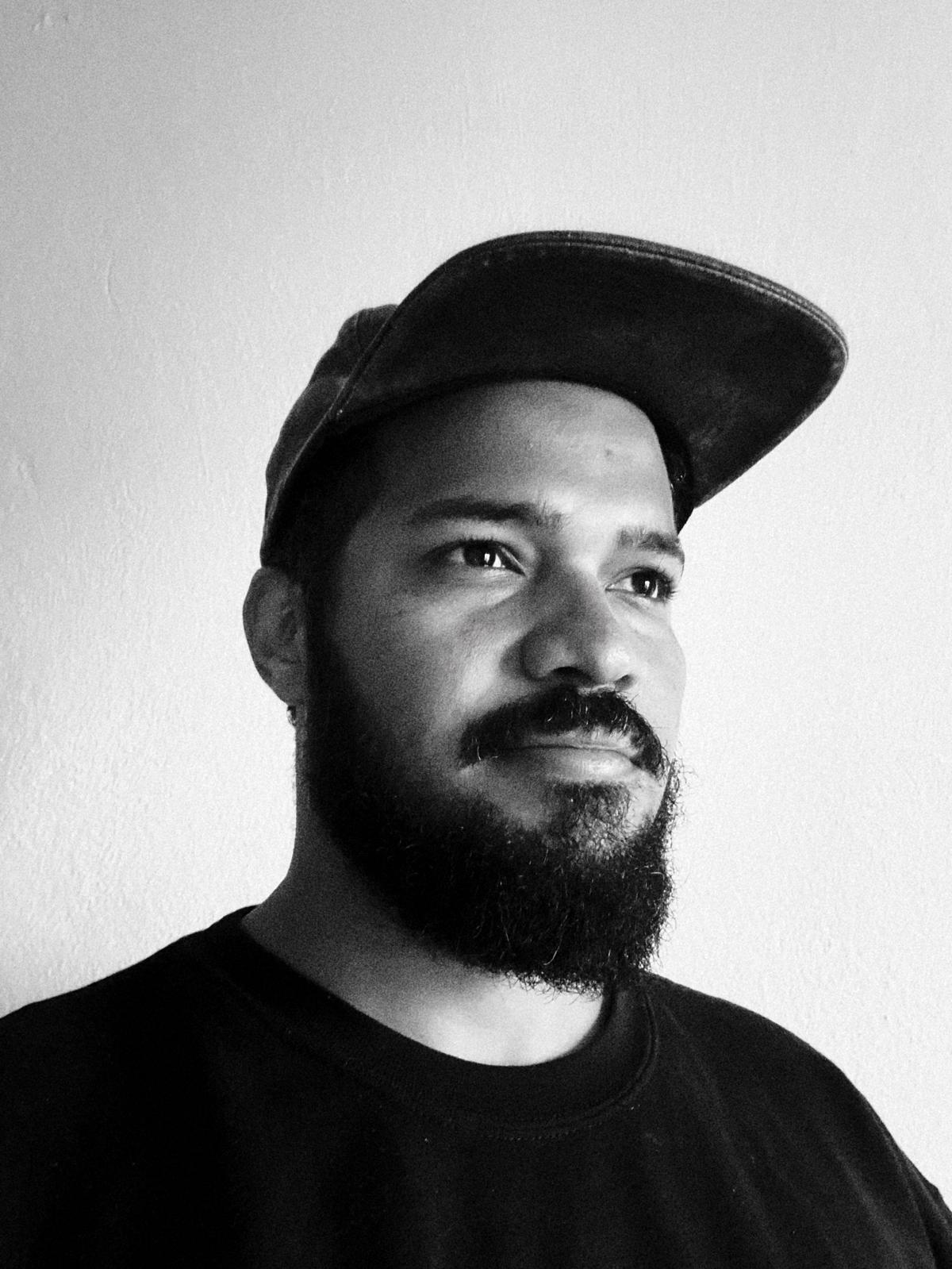 A thoughtful young person with dark hair gazes to the side, captured in soft black and white lighting.