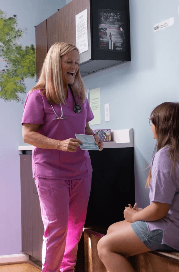 Nurse Practitioner holding information card, speaking to patient.