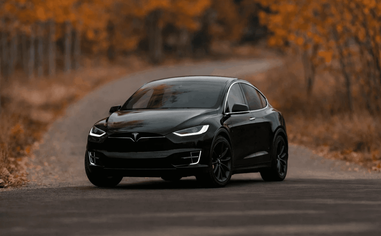 Black Tesla Model X providing executive chauffeur service on a scenic road in Provence tailored for VIP clients