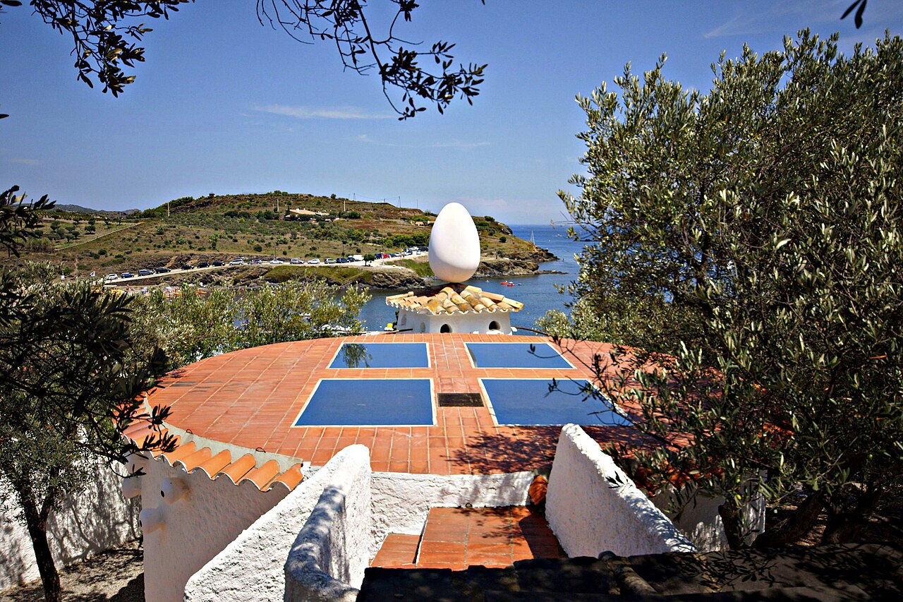 The red roof of the Dali House Museum featuring a large sculpture of a white egg. 