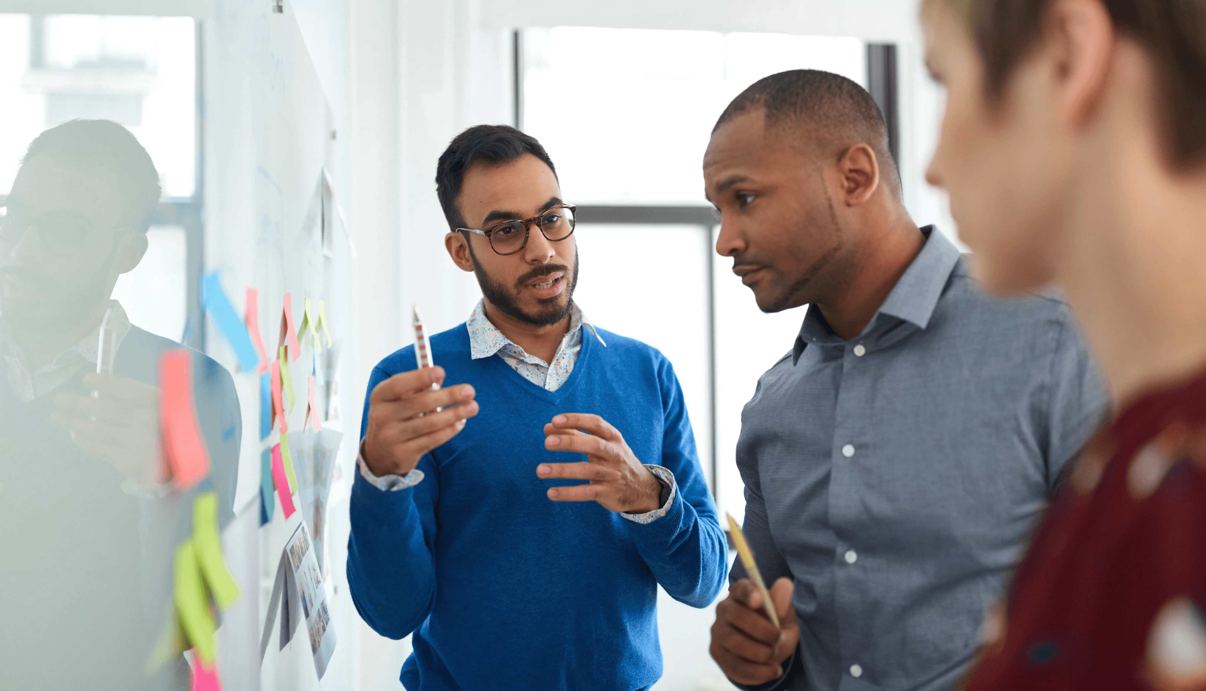 Team organizing sticky notes during qualitative research analysis and affinity mapping