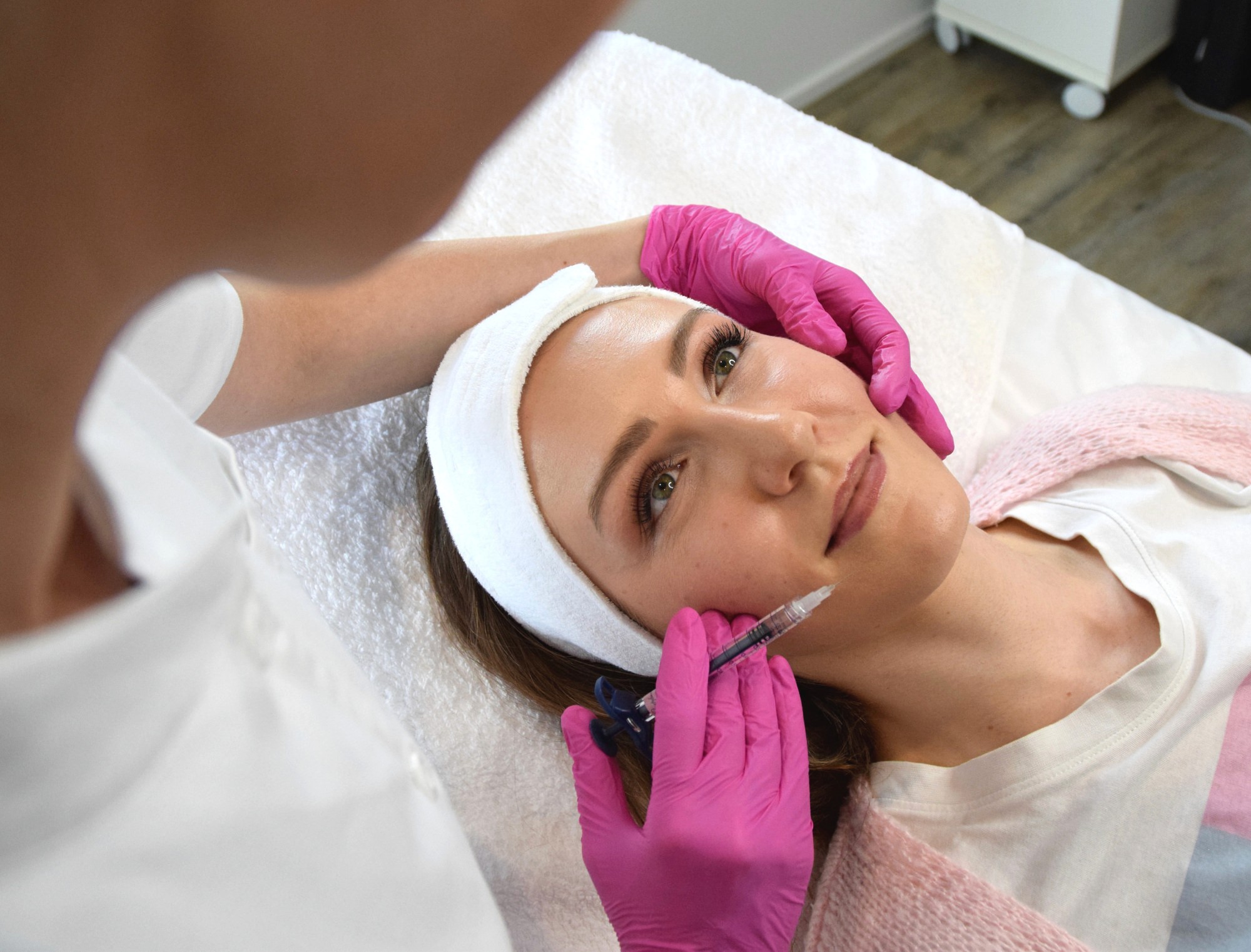 Nahaufnahme einer Schönheitsbehandlung im Gesicht, bei der Hyaluronsäure mit einer feinen Kanüle zur Faltenunterspritzung injiziert wird.