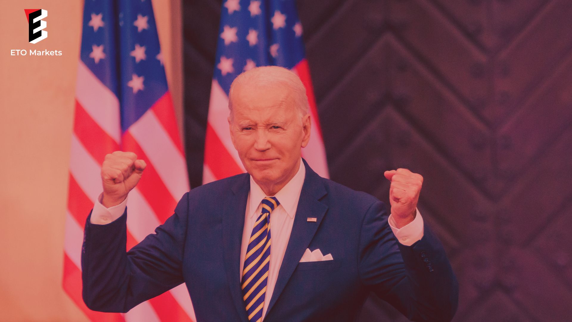 Joe Biden raises his fists triumphantly in front of American flags.