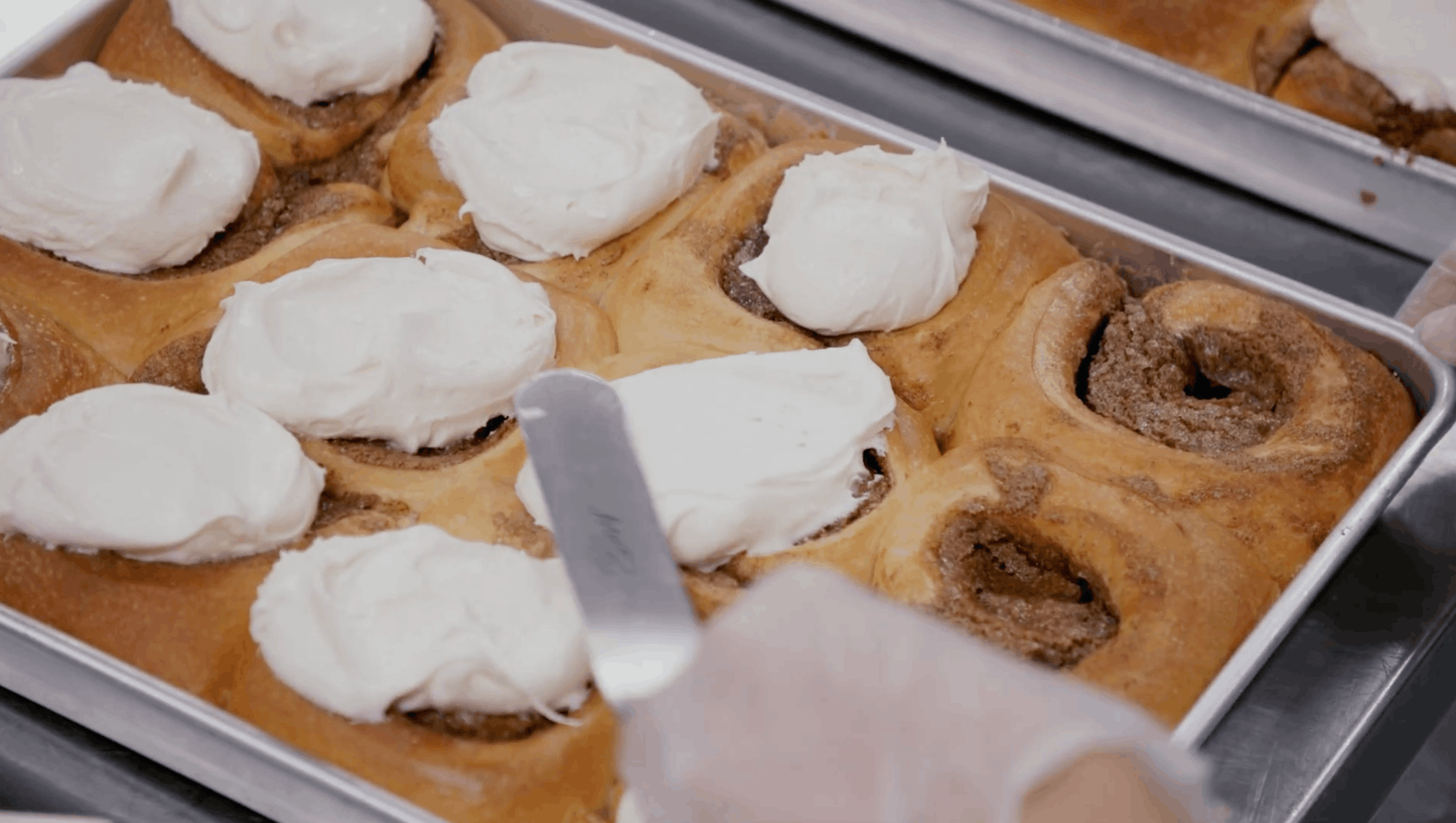 a batch of 12 cinnamon rolls gets frosted in a cloudkitchen