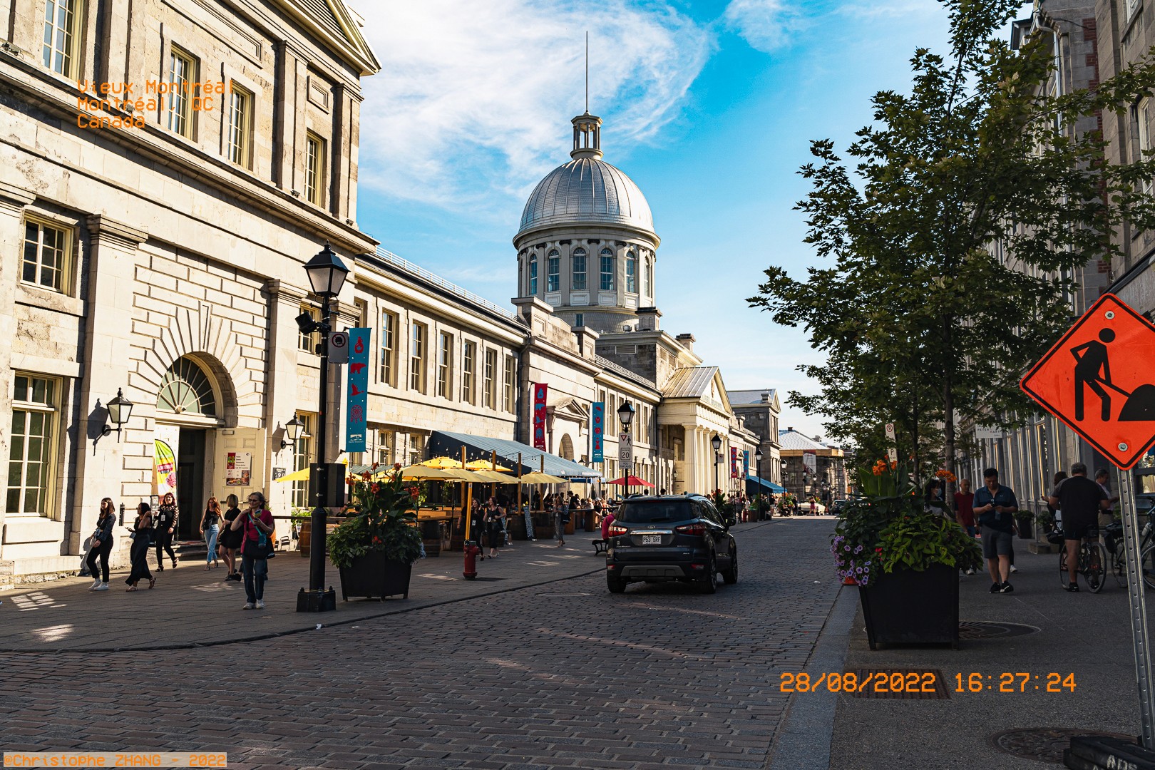 Rue animée du Vieux-Montréal avec bâtiments historiques et terrasses.