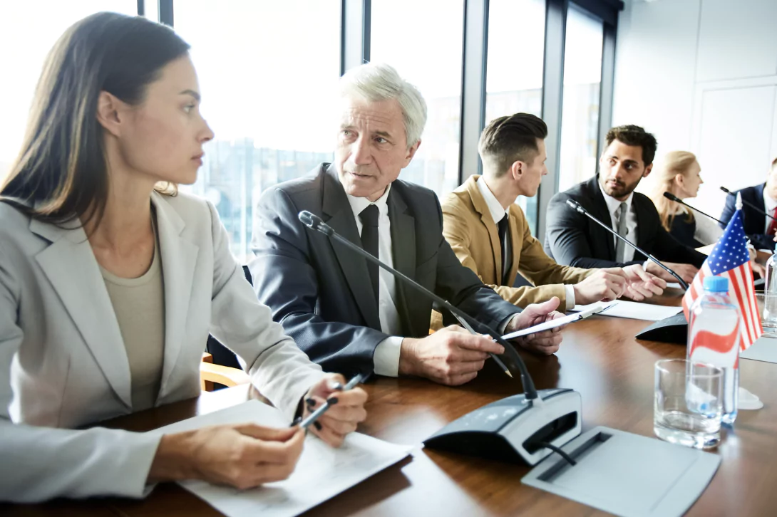 A man and a lade talking at a big conference table