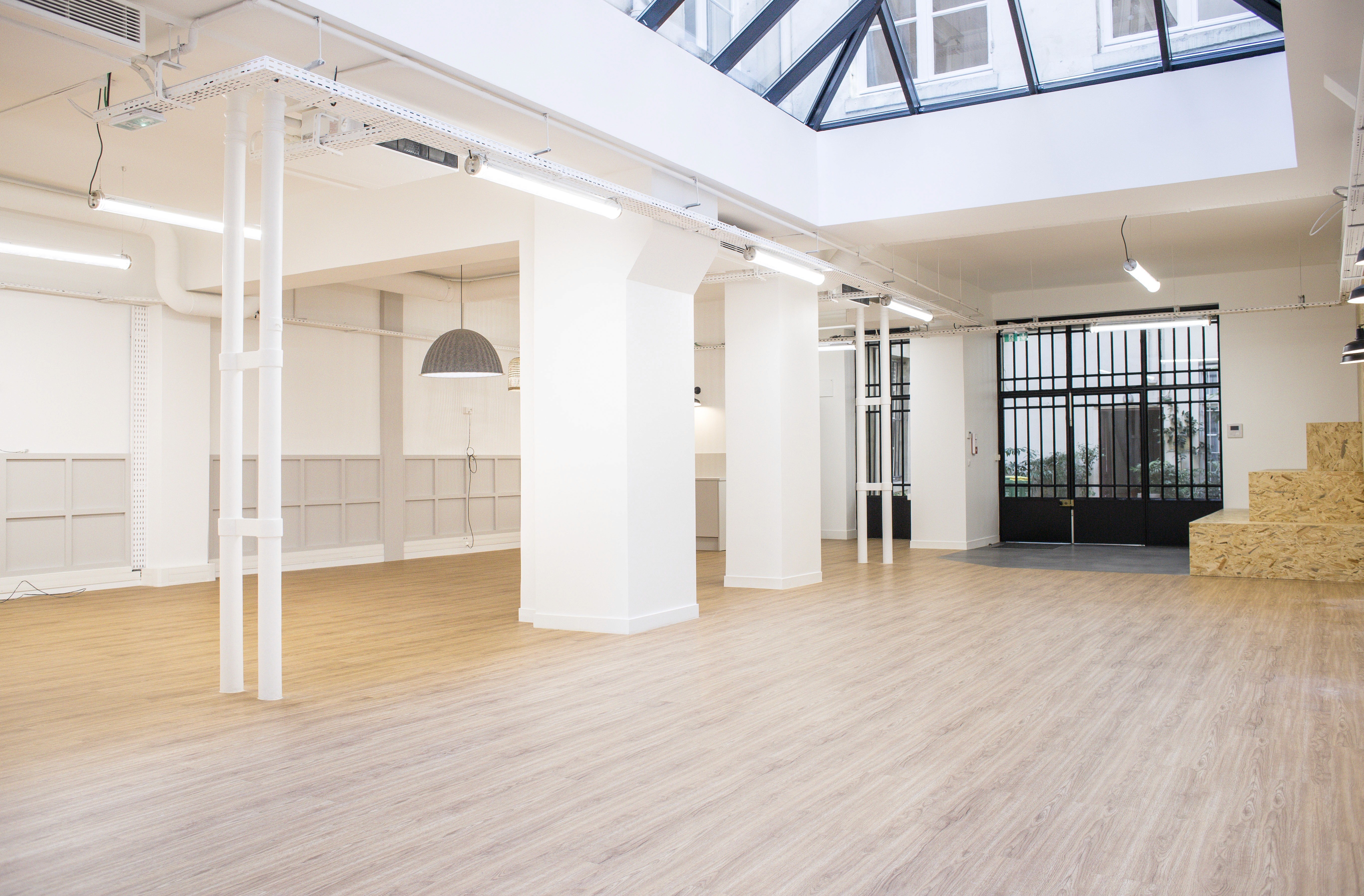 Espace showroom lumineux de l'agence Clothette avec parquet clair, murs blancs minimalistes et verrière