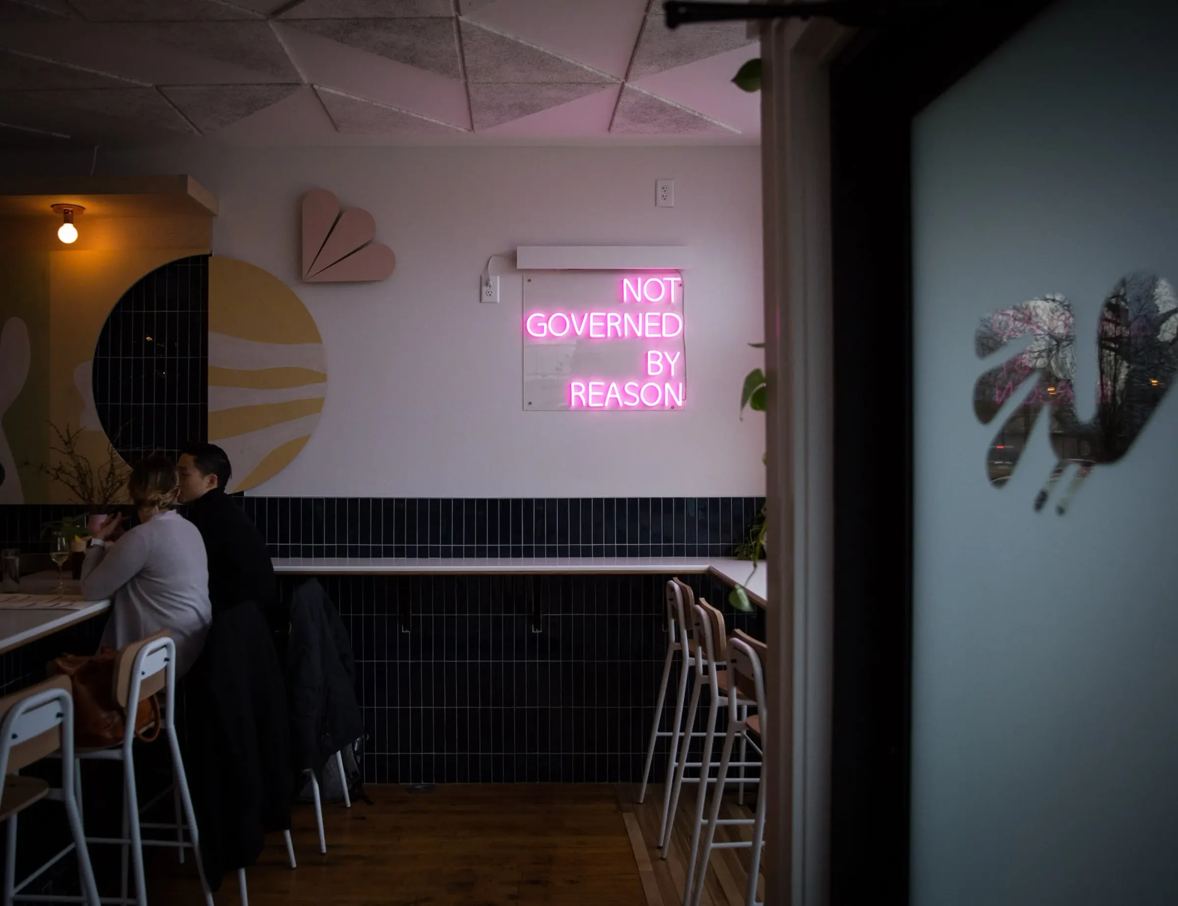 Navy tile bar and Not Governed By Reason neon sign at Law Bird
