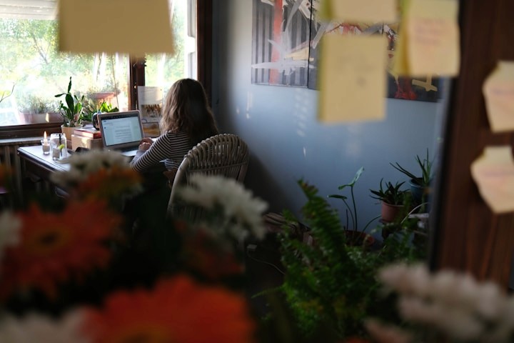 A professional working at a desk in a calm, plant-filled workspace.