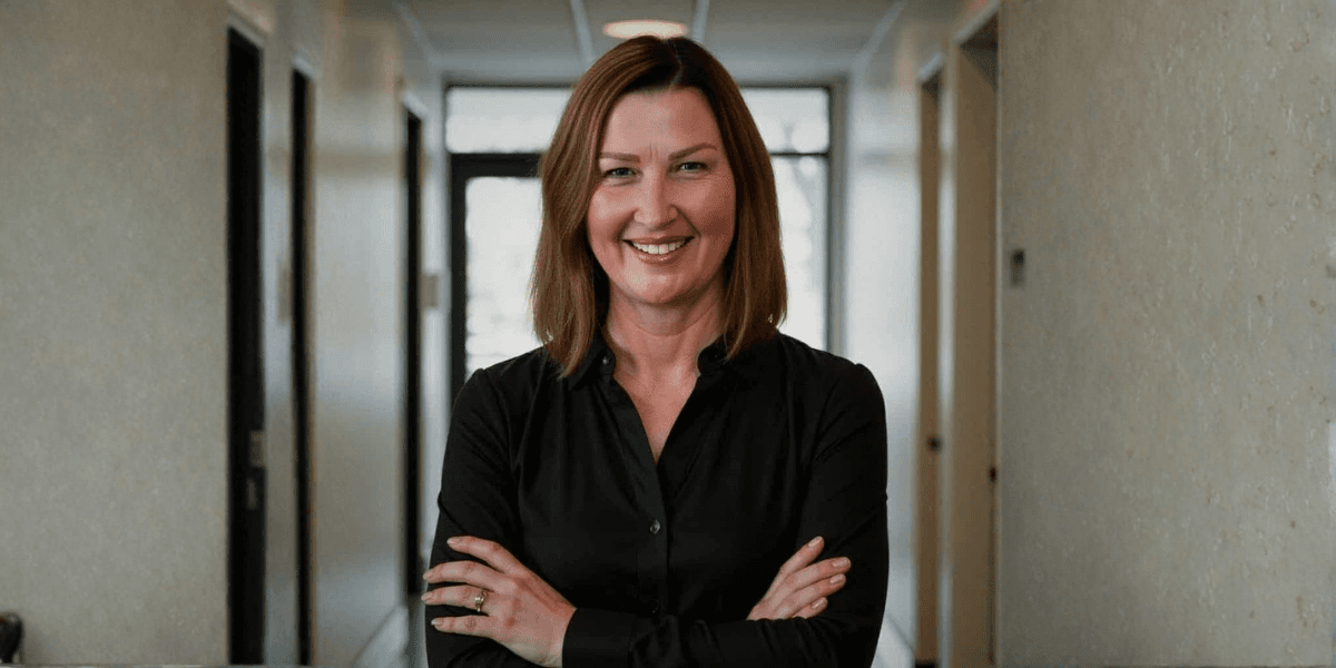 Renee West, founder of Intariq, smiles confidently in a hallway, symbolizing empowerment and human-centered AI for business owners.