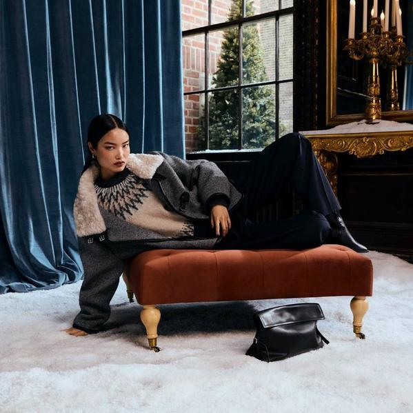 Woman wearing fairisle jumper laying on a brown chaise