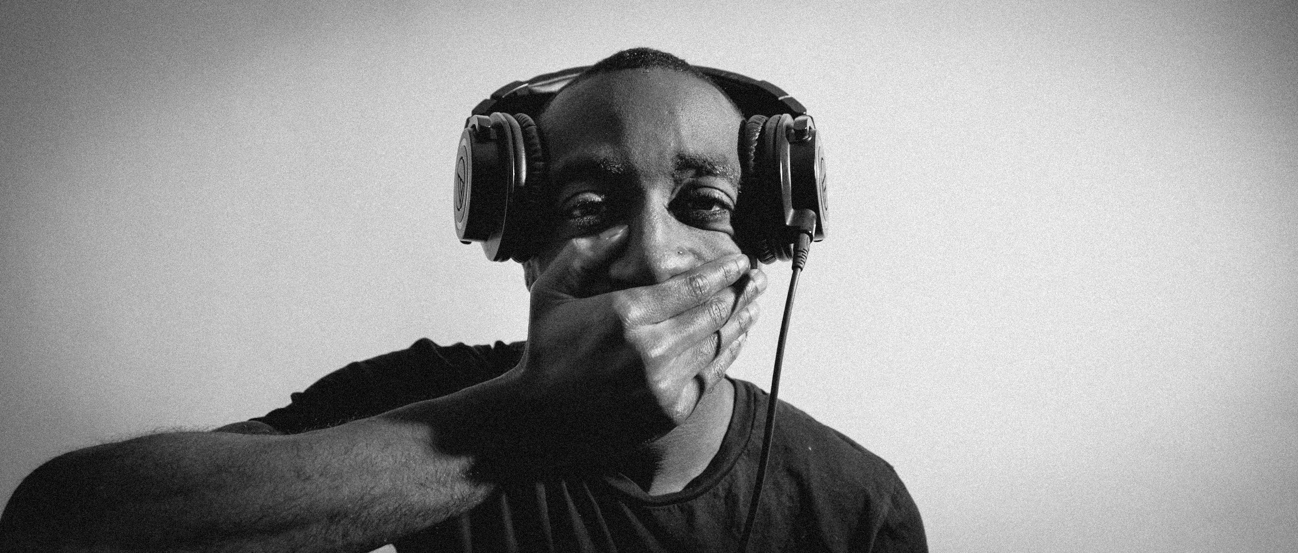 Man with headphones and covering his mouth