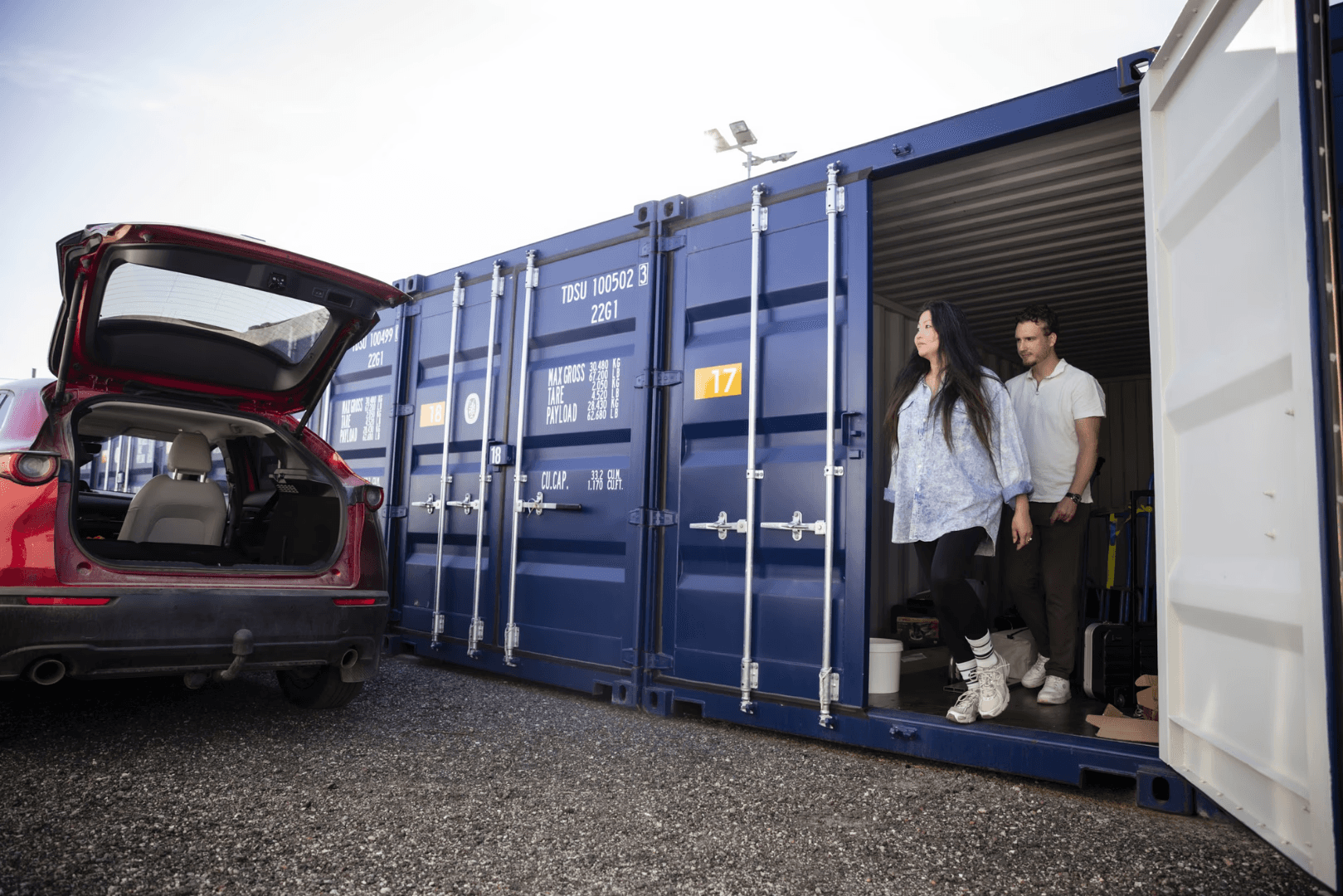Containerförråd med orange soffa och staplade flyttkartonger i belyst lagerutrymme