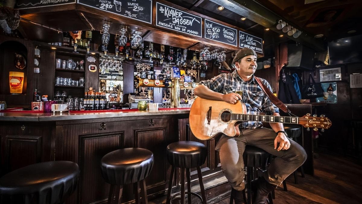 A guitarist performing at the end of a bar