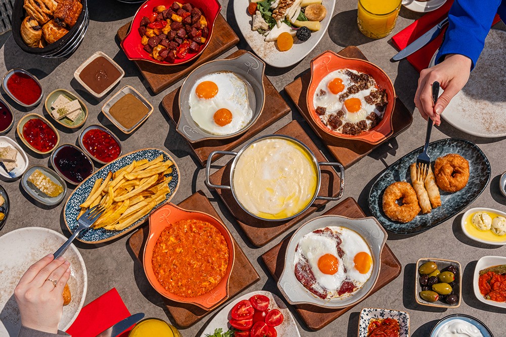 Traditional Turkish breakfast spread with eggs, cheeses, olives and jams served on a shared table in Istanbul.