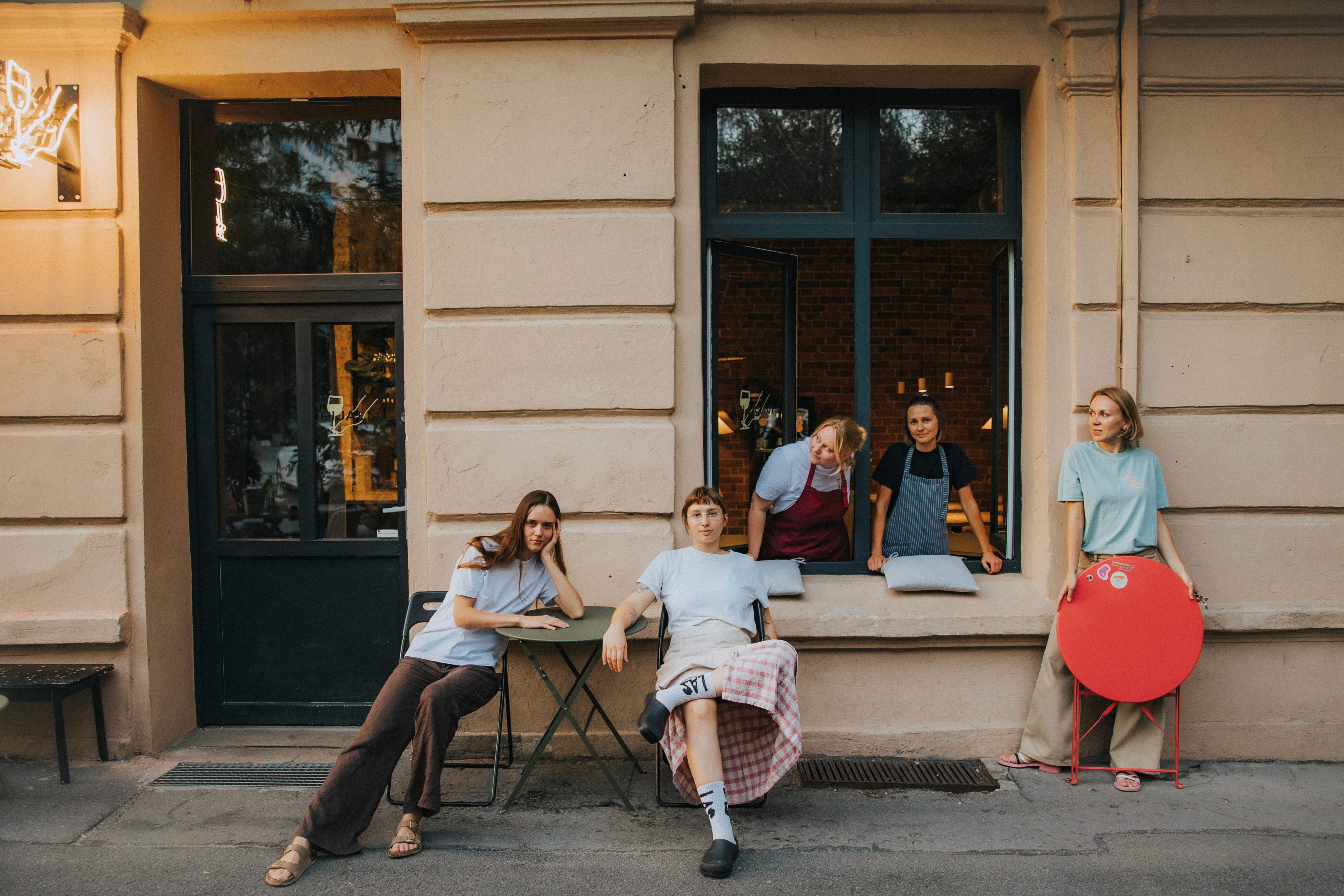 Ręka trzymająca kieliszek bursztynowego wina, częściowo zakryta jasną kurtyną w tle.