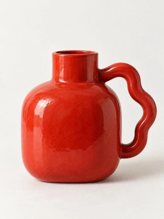 Tomato-red Loop vase with an oversized wavy handle, photographed in the studio