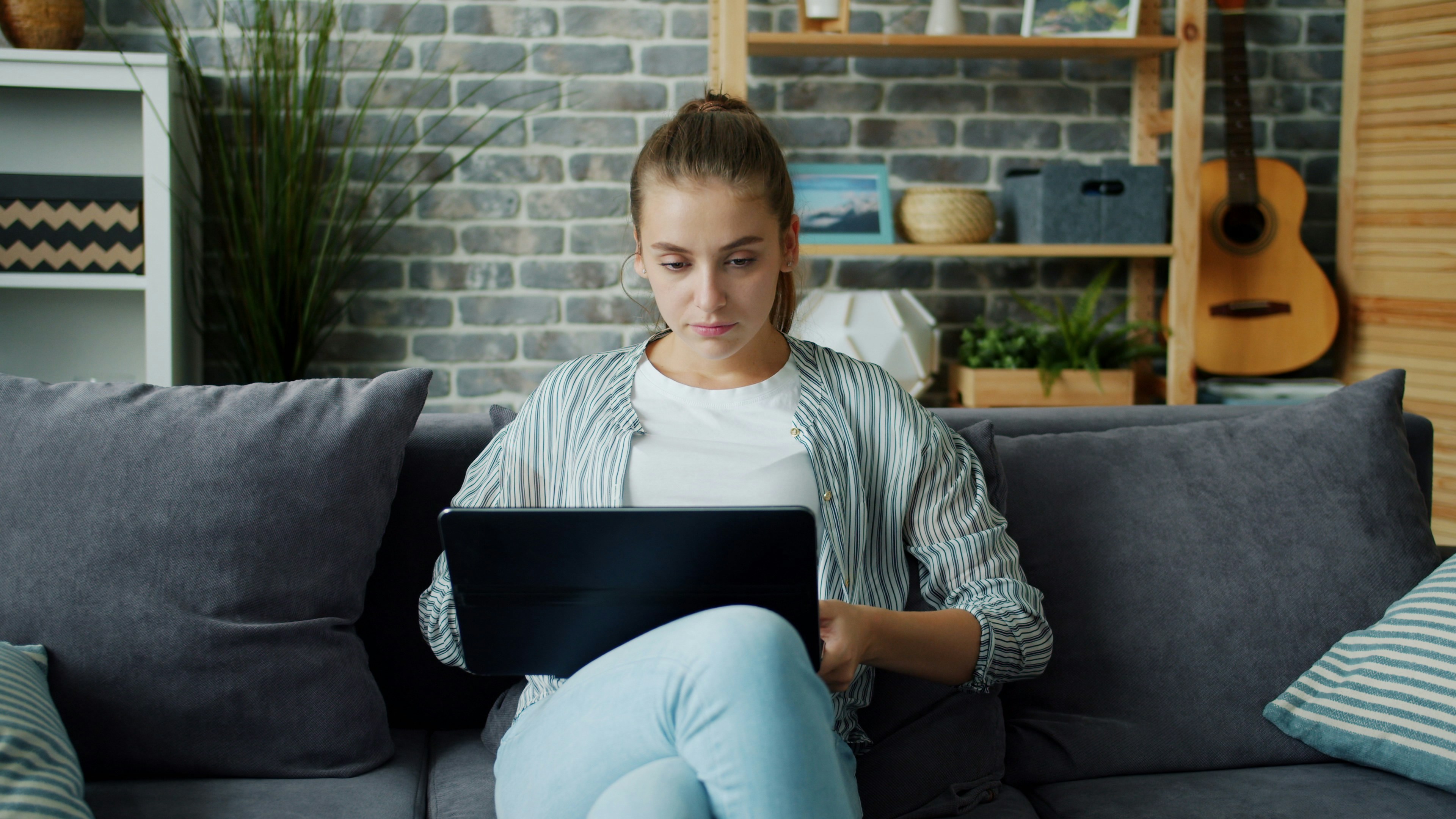 Young woman working on laptop on couch