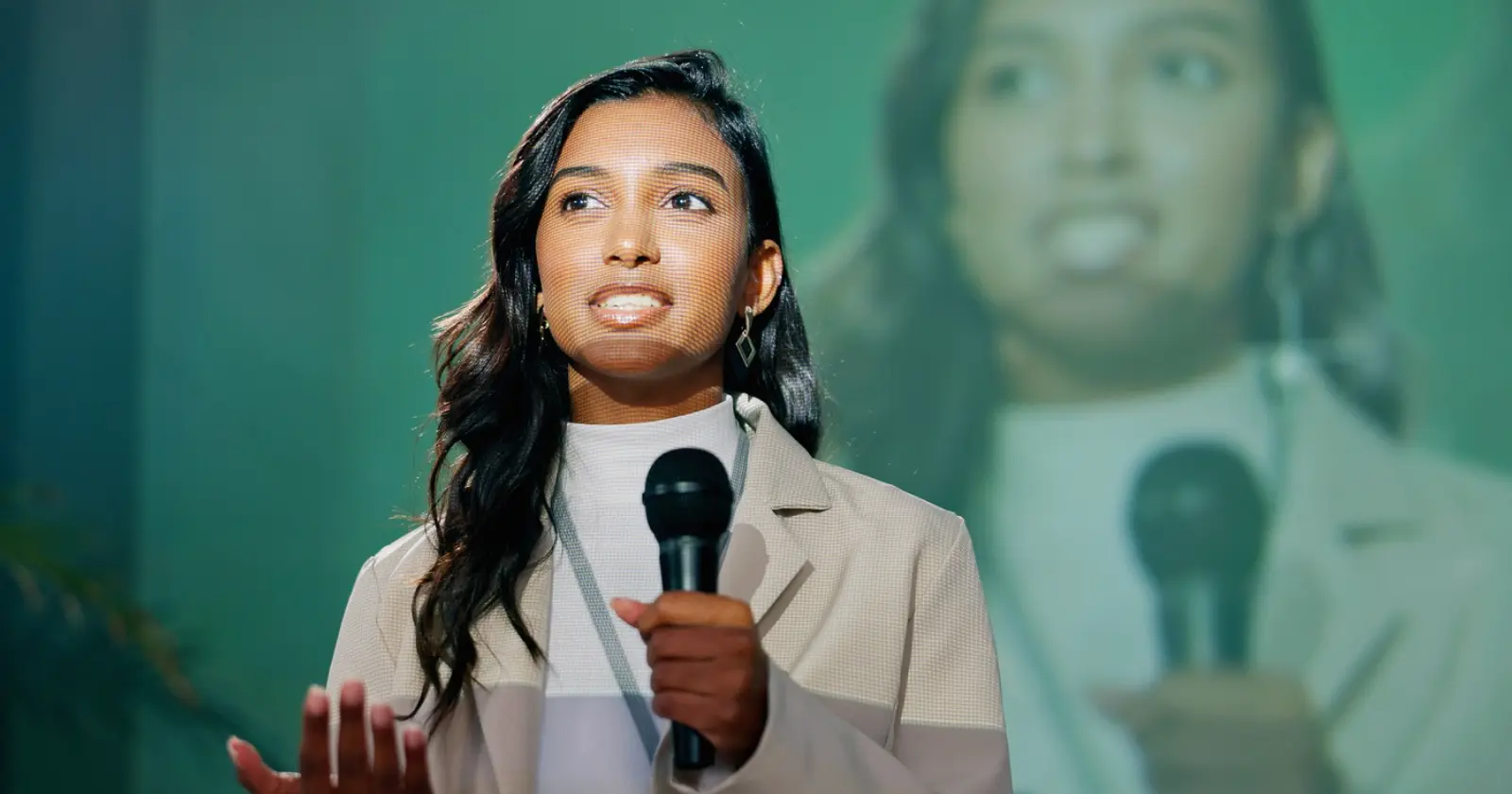 Business leader speaking confidently with a microphone in front of a projected screen, illustrating clear communication of strategic priorities