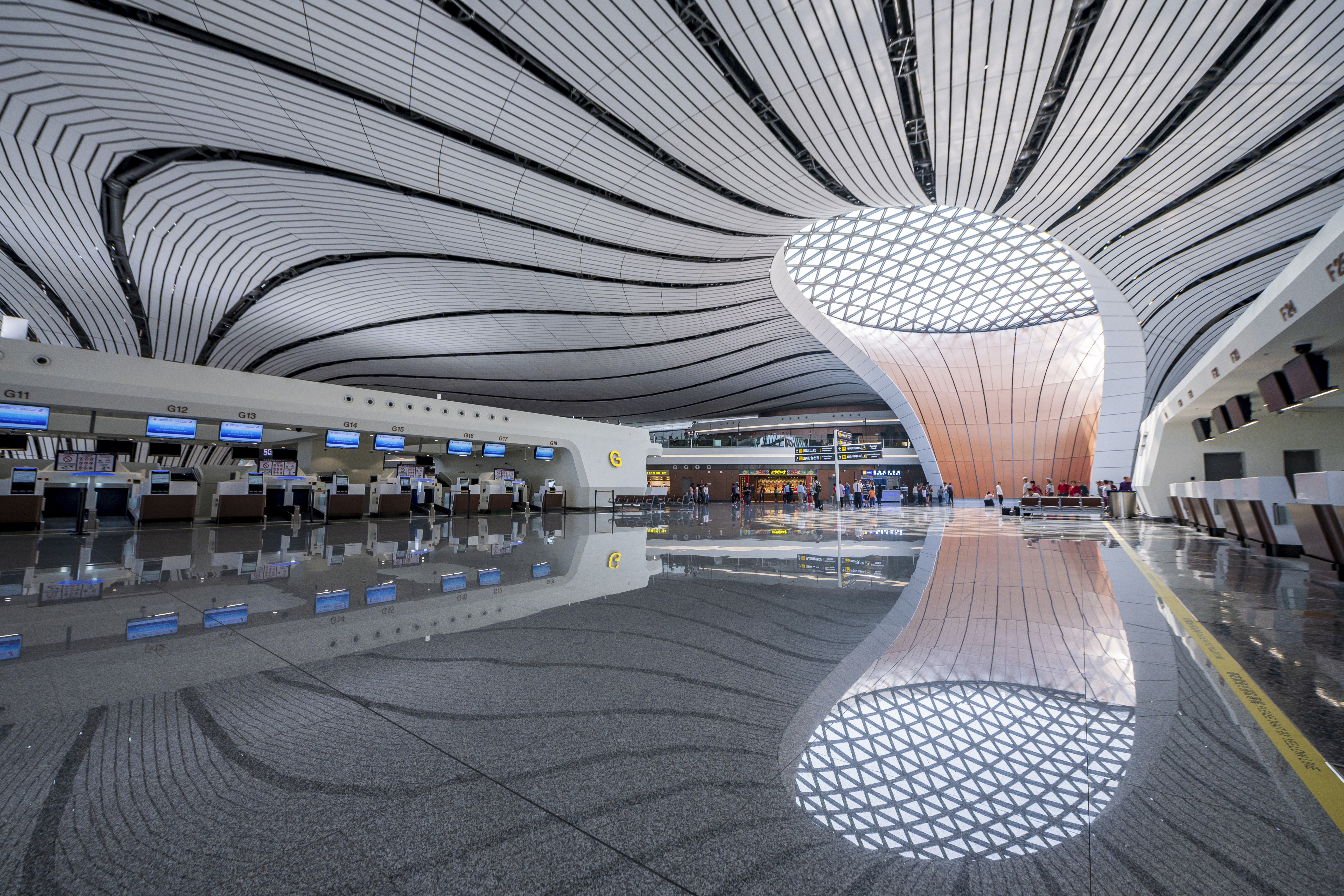 師傅穿著專用釘鞋在室內場地進行白色環氧樹脂自流平地坪施工，使用長柄刷子均勻鋪設耐磨地漆。