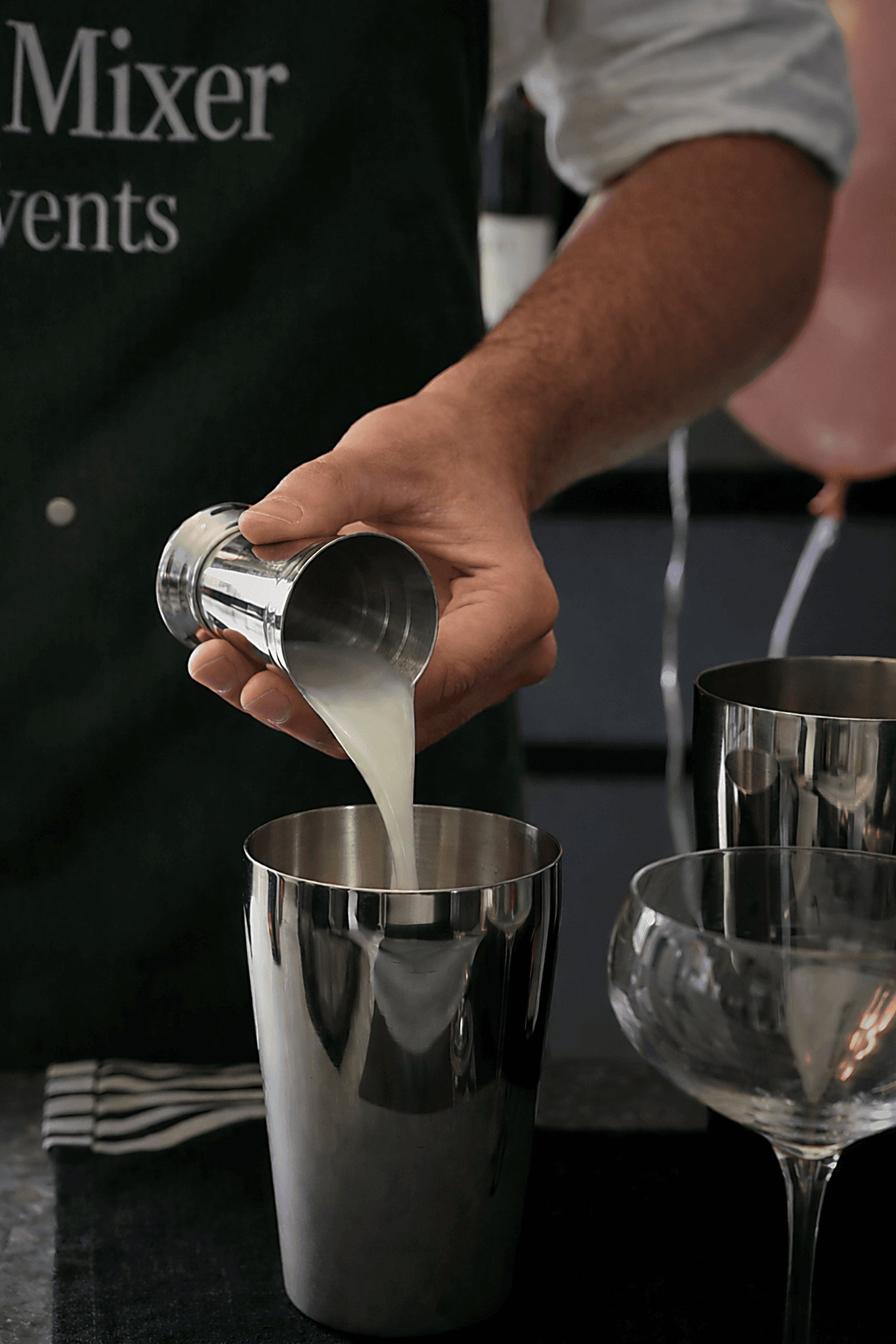 Bartender pours citrus juice from jigger into shaker