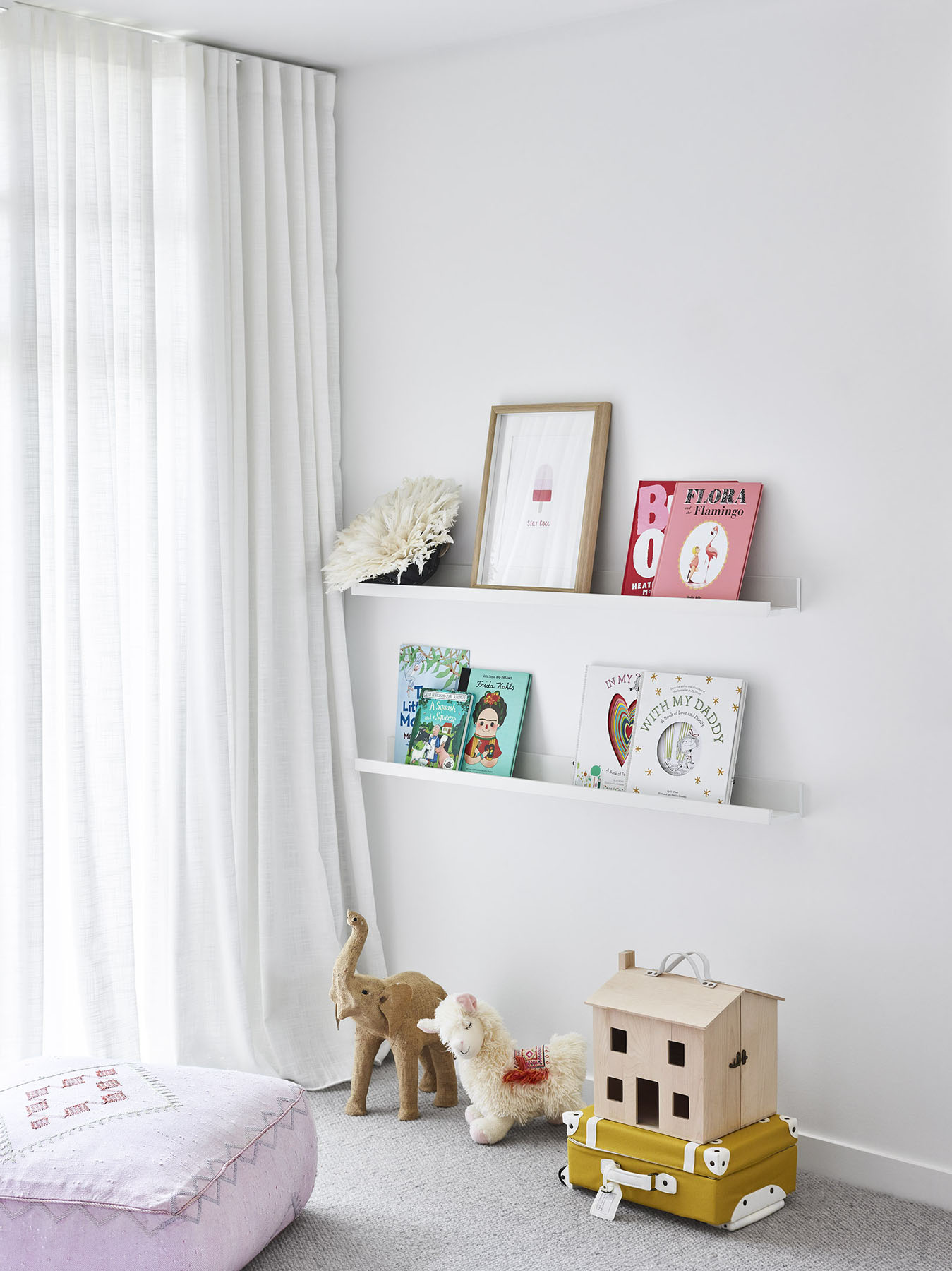 Children’s room with white shelving, books, and soft toys.