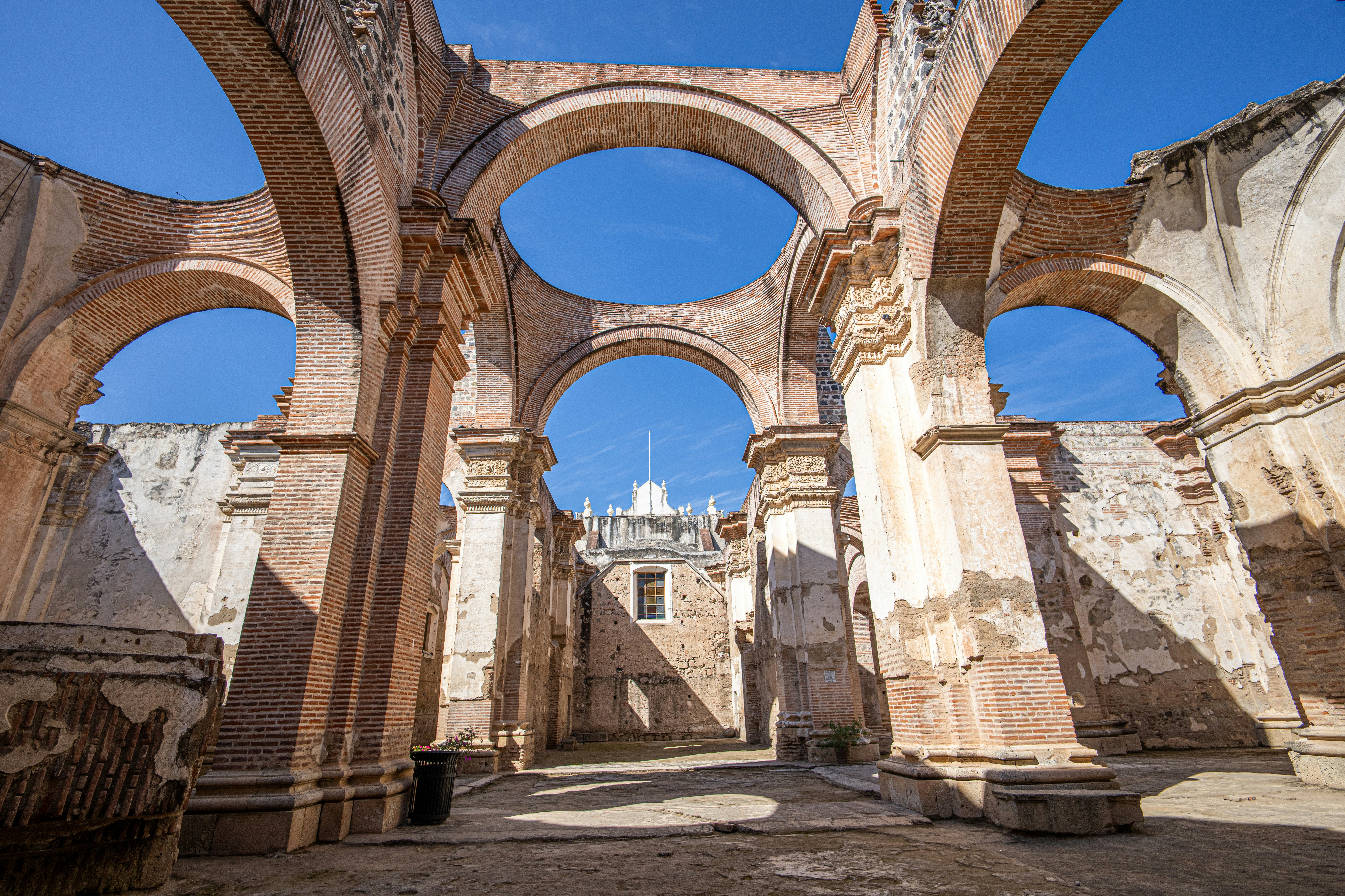 Ruins of an ancient church with towering brick arches standing against a clear blue sky, showcasing weathered walls and intricate architectural details.