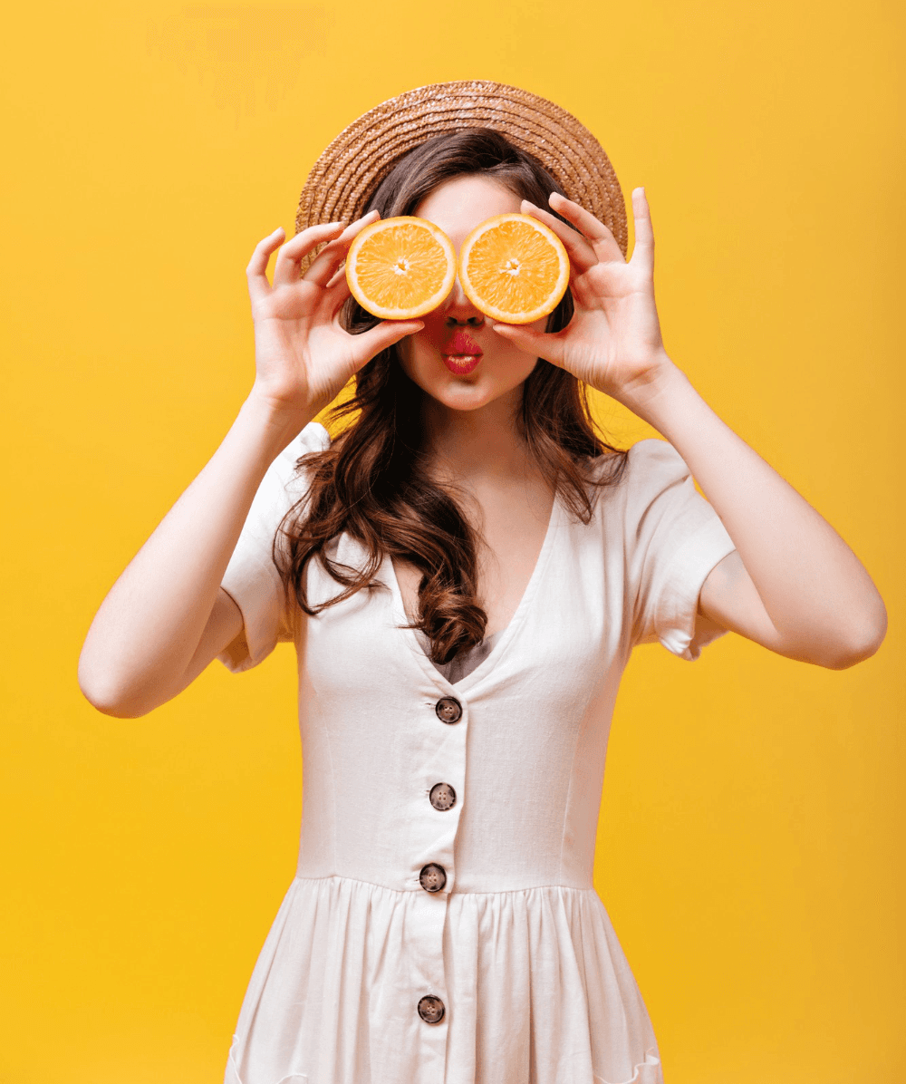 Femme énergique et souriante s'amusant avec des oranges, faisant le plein de vitamine C pour le défi #boosttonmicrobiote.