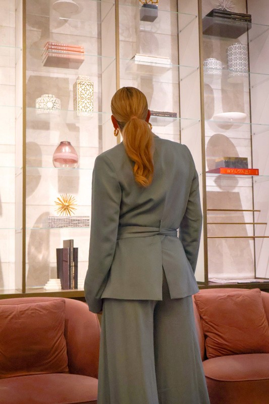 woman in a blue suit faces away, looking at decorations