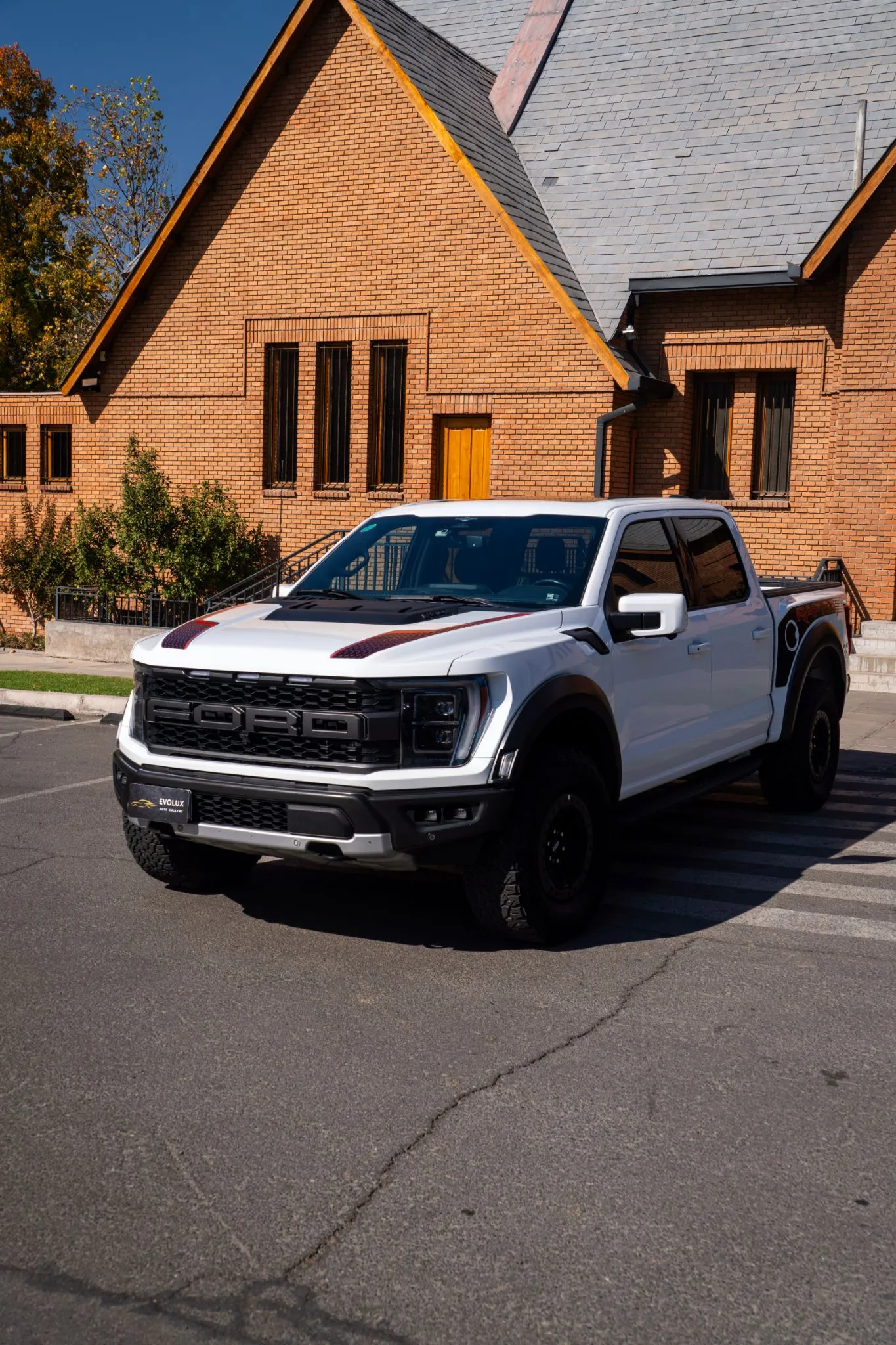 Ford F-150 Raptor blanca estacionada en exterior, vista frontal lateral con parrilla negra FORD