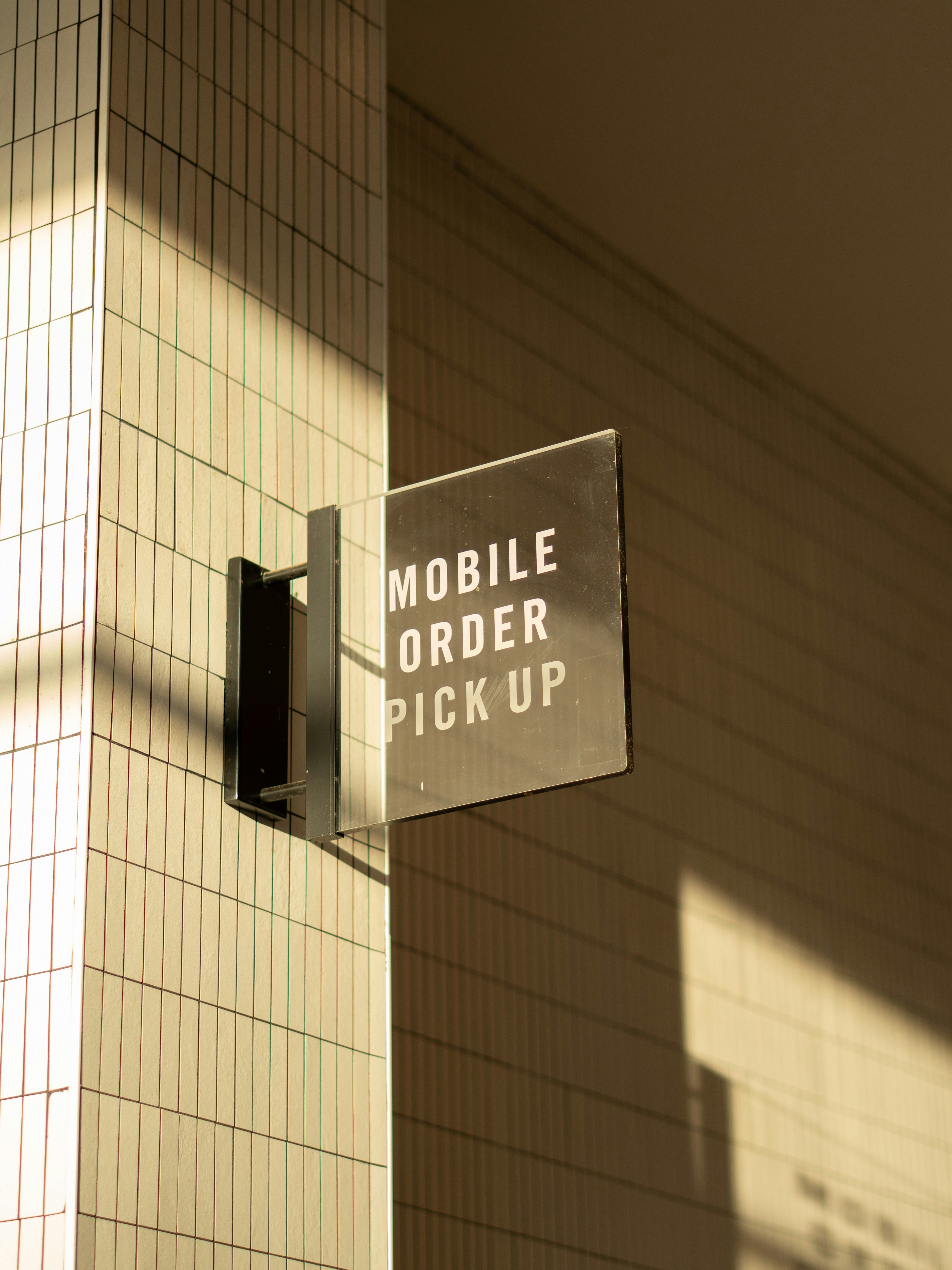 Sign for mobile order pick up on a tiled wall.