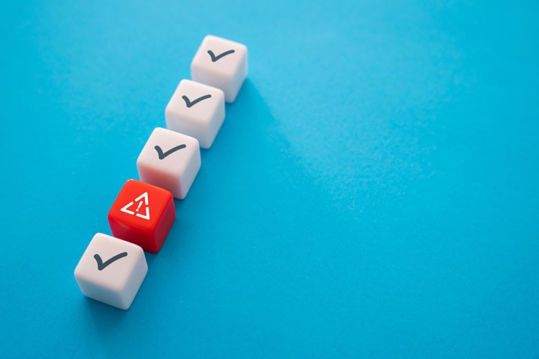 Five blocks laying on a blue table, one of the blocks is distinctly red as opposed to white.