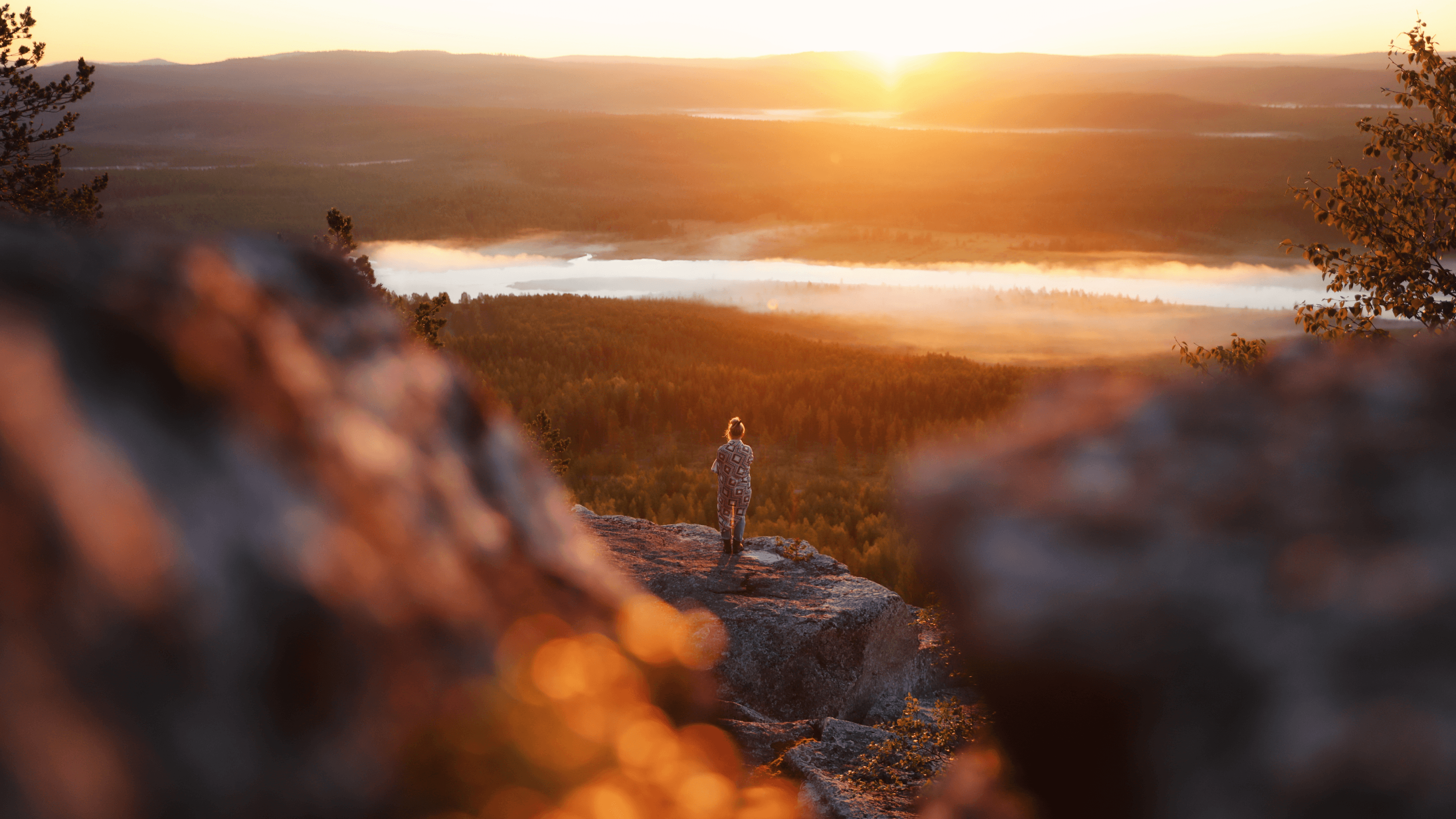 A woman standing on a cliff at sunset