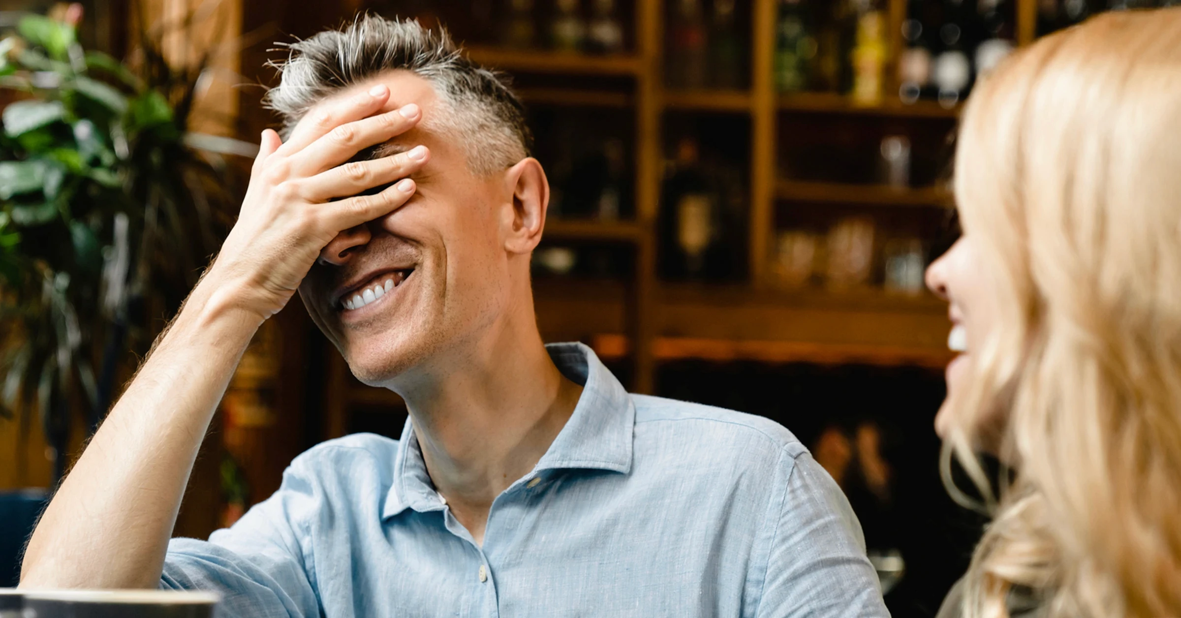 Man ler med ena handen på ansiktet, signalerar att han har sagt eller gjort något pinsamt inför sin dejt.