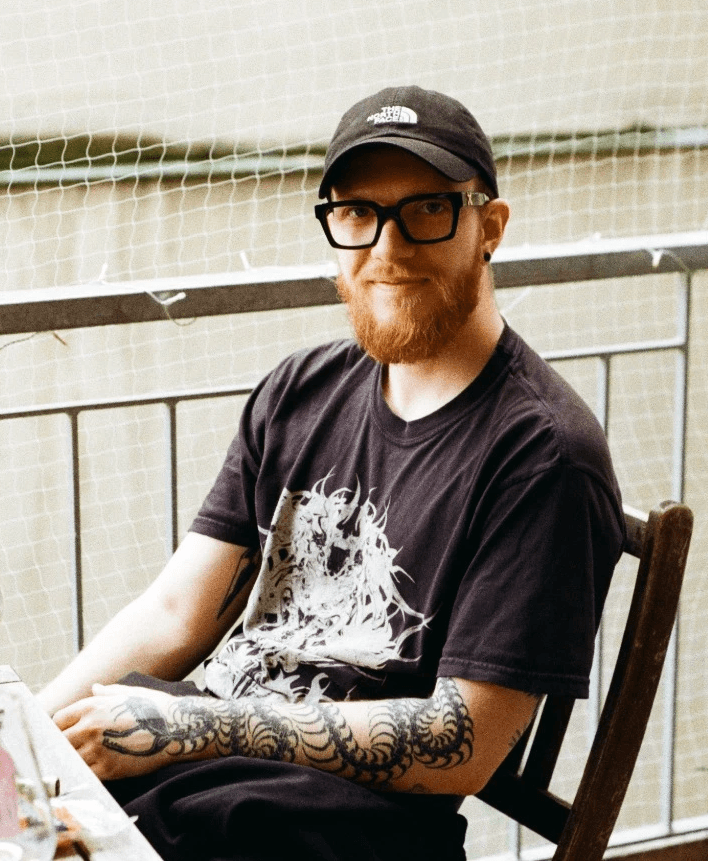 A thoughtful young person with dark hair gazes to the side, captured in soft black and white lighting.