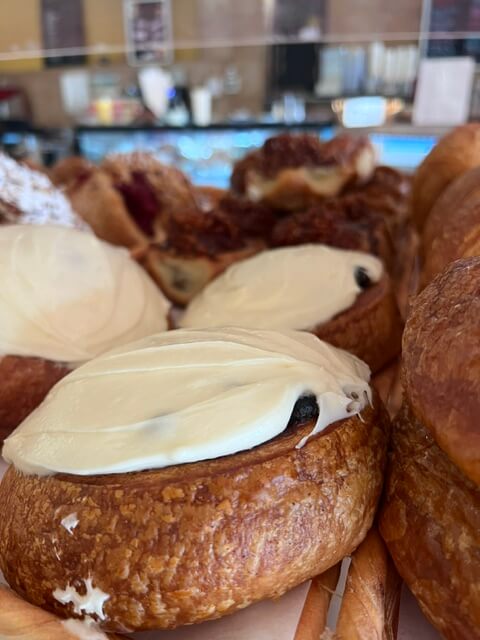 A close-up of cinnamon rolls under a thick layer of cream cheese icing.