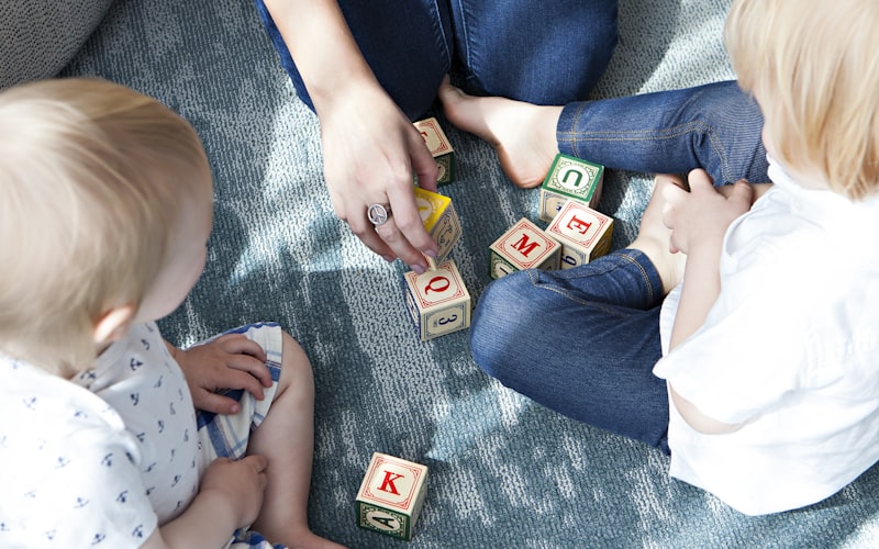 Two young children playing side-by-side with colorful alphabet letter blocks.