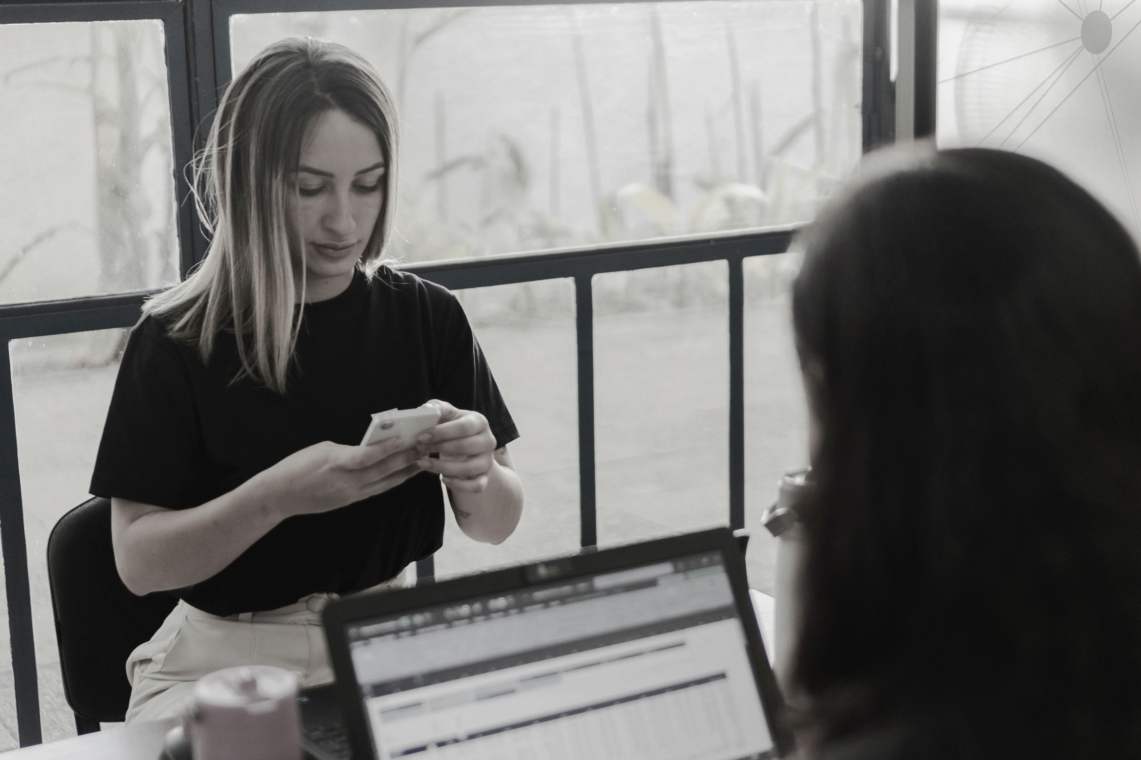 Two women working at a desk with a laptop.