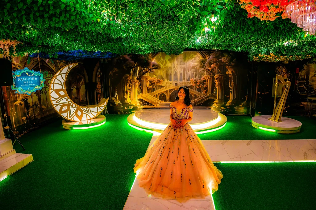 Debutante in a peach gown walking past the crescent moon at Pandora Hall
