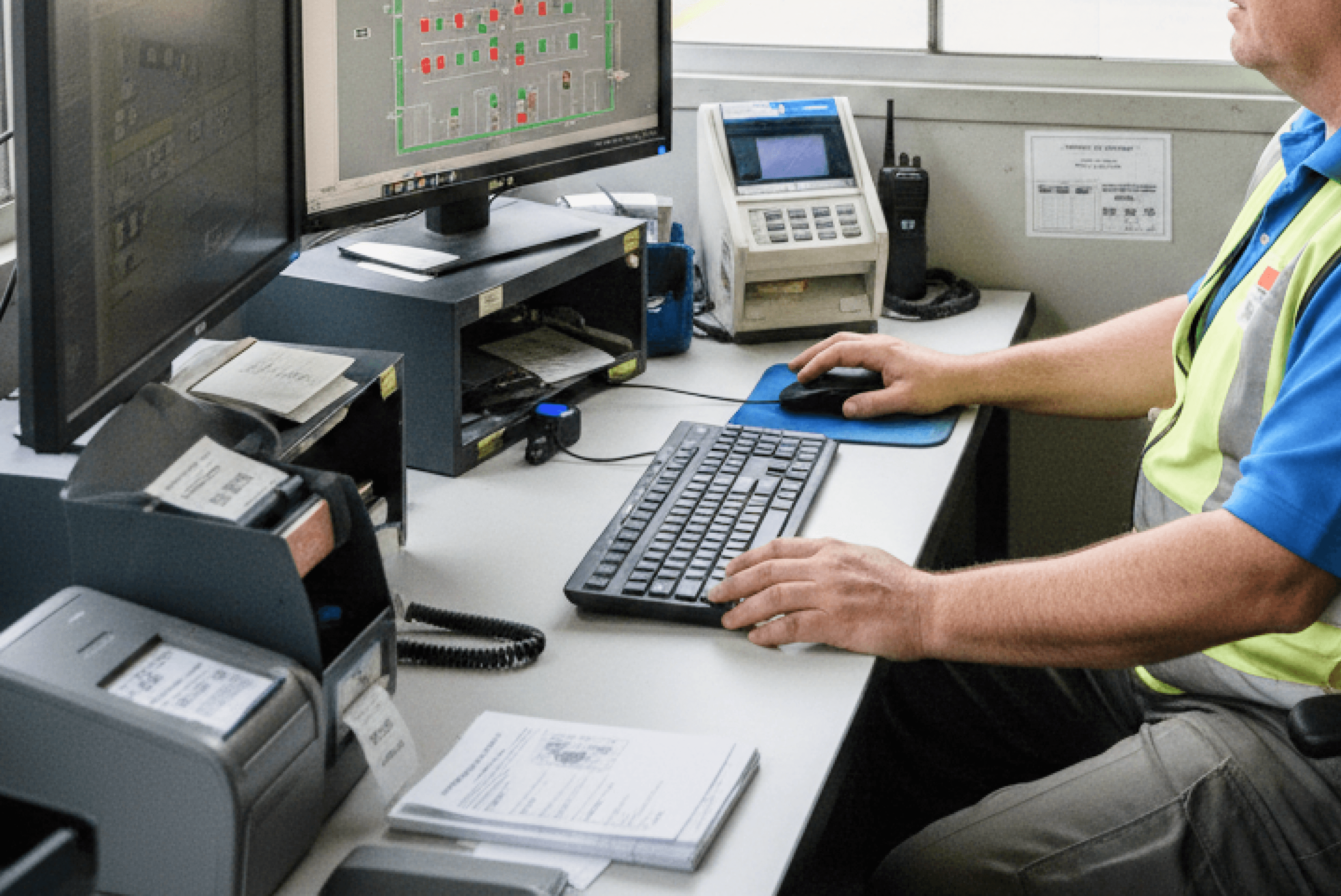 주차 관리 직원이 책상에 앉아 모니터를 통해 주차 구역의 실시간 점유 현황과 차량 등록 데이터를 확인하며 업무를 보는 모습입니다.