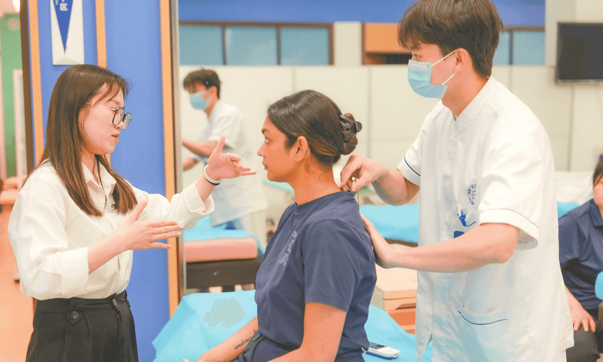 A group of healthcare students practice techniques on a patient in a clinical setting.