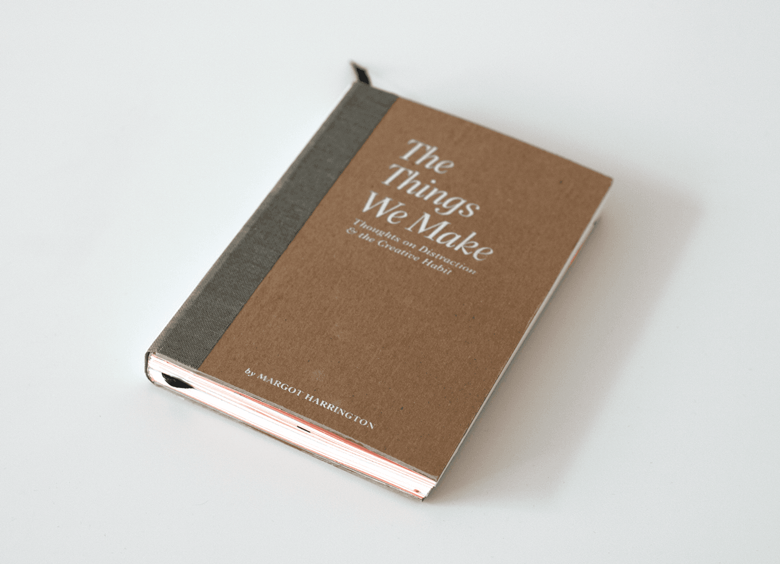 Book cover photo on an angle. Cover is thick brown craft cover stock, white screen printed title, gray spine wrap, and black ribbon