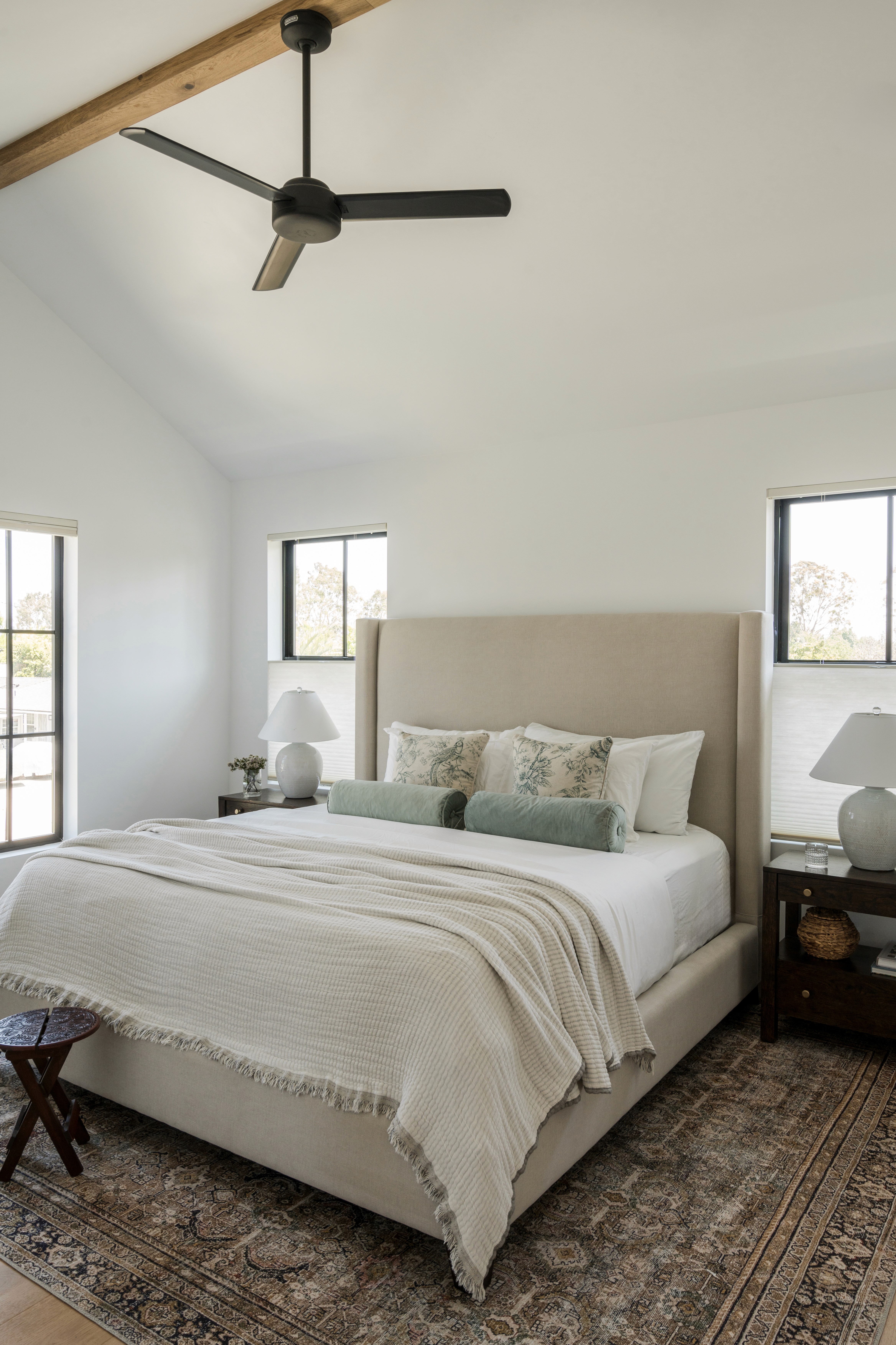 A serene and spacious primary bedroom featuring soft neutral tones and plush bedding, while large windows let in natural light by Jubilee Interiors in Lakewood, California