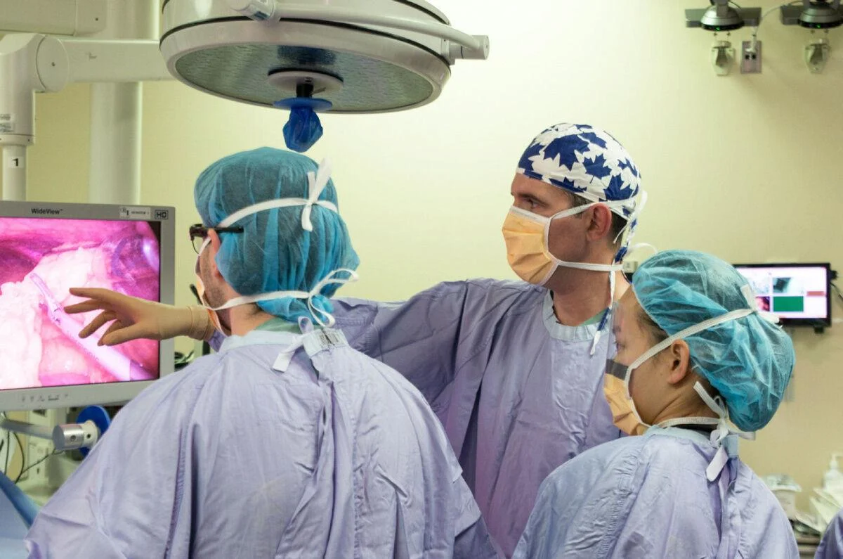 Surgeons in operating room, looking at screen.